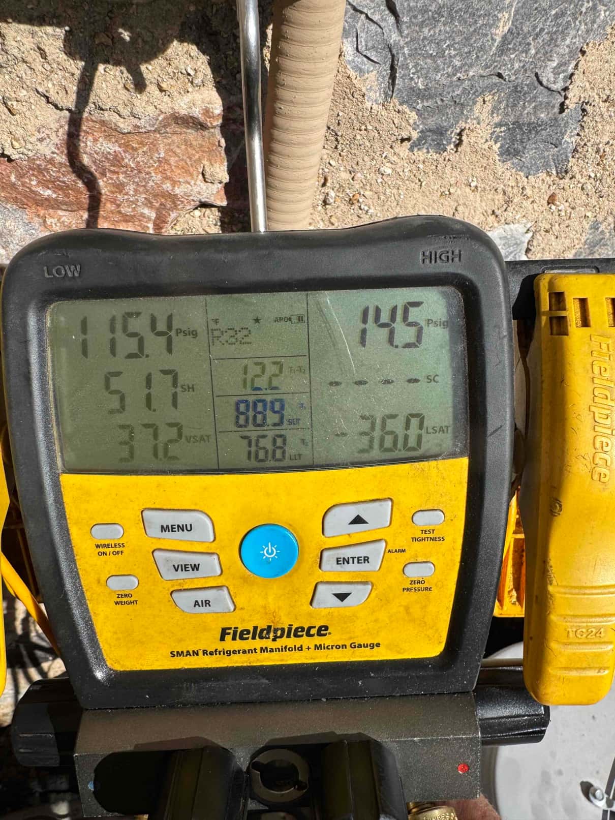 Digital manifold shows system operating pressures with suction at 115 PSI and liquid at 145 PSI during commissioning.