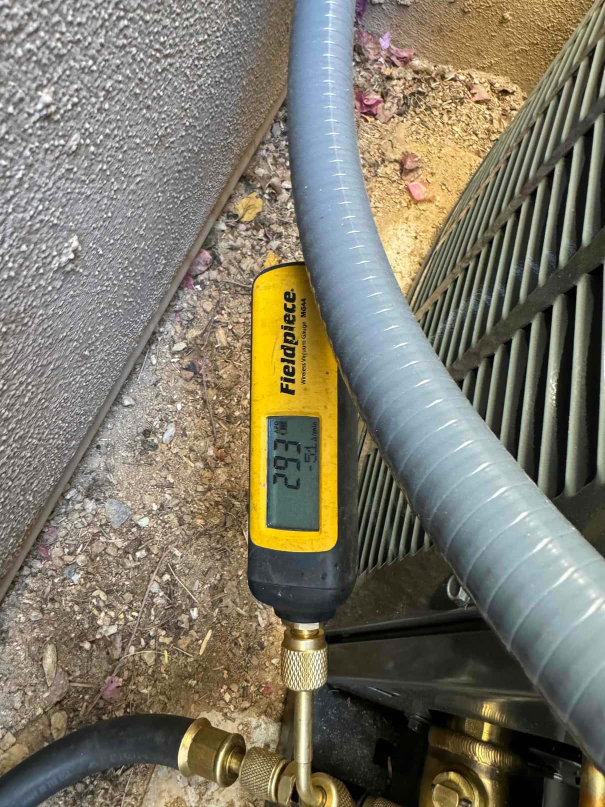 Digital micron gauge connected at the outdoor unit reads 293 microns, confirming a deep vacuum before charging.
