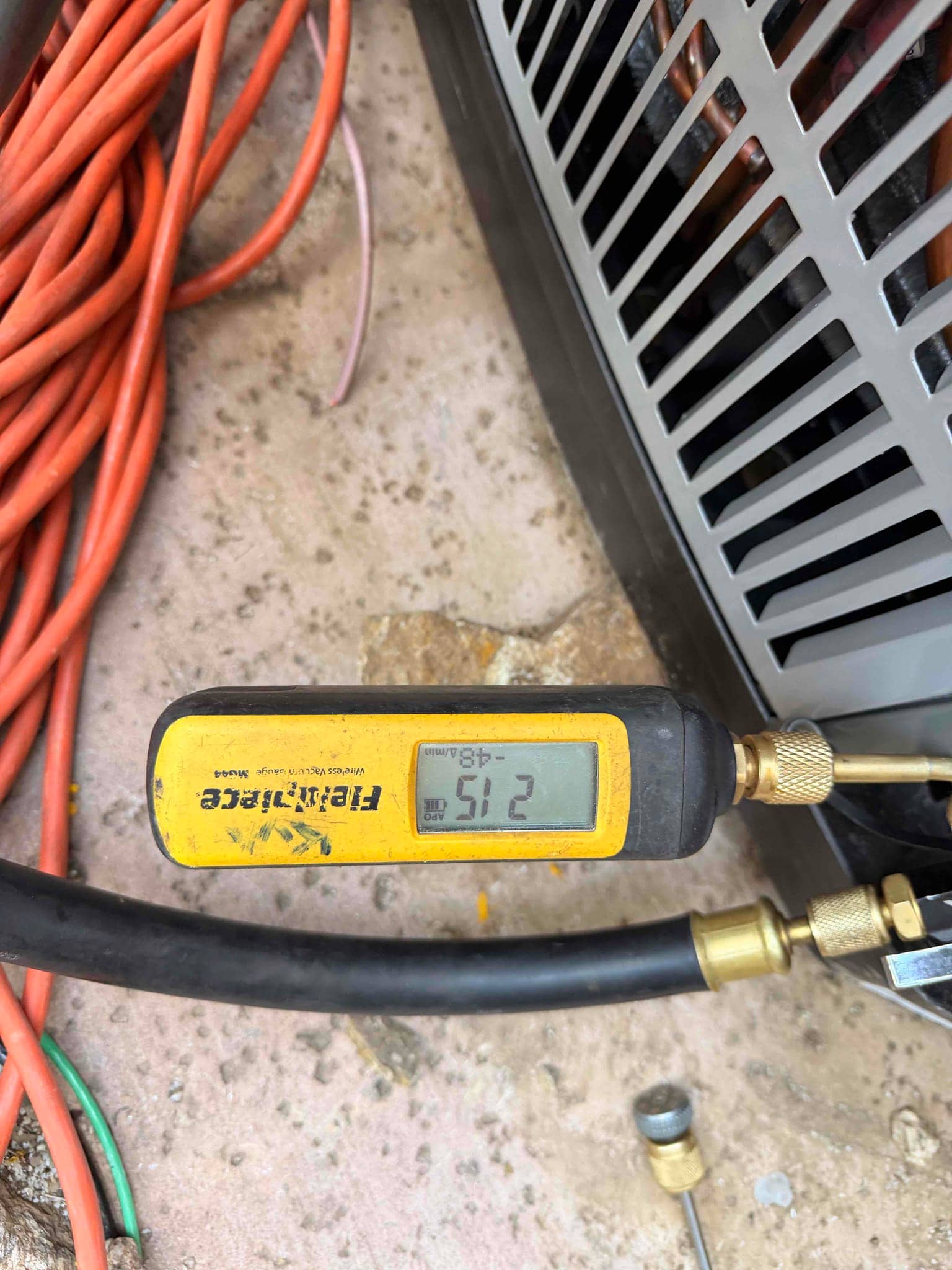 Digital micron gauge connected at the outdoor unit shows 512 microns during the evacuation phase before charging.