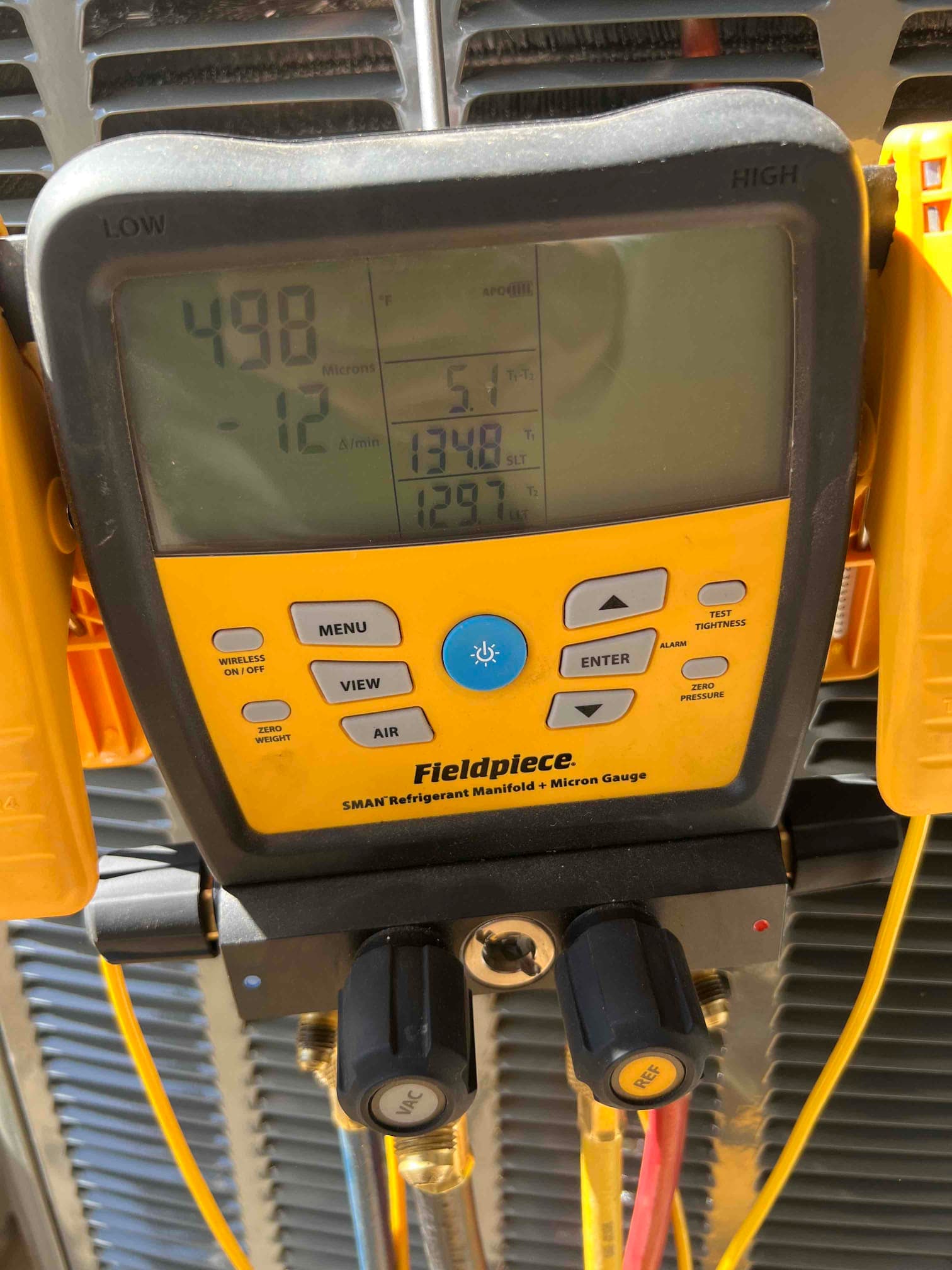 Digital micron gauge on the manifold shows 498 microns during system evacuation prior to refrigerant charging.