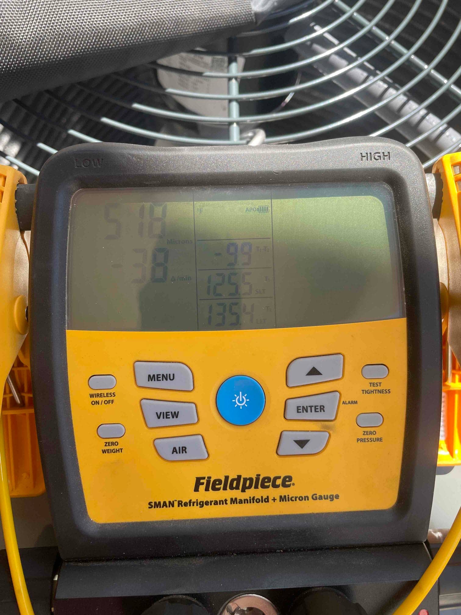 Digital micron gauge on the outdoor unit shows a deep vacuum achieved during system evacuation prior to refrigerant charging.