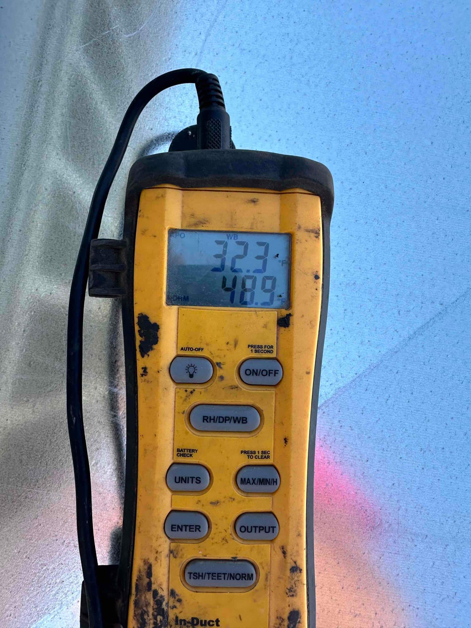 Digital probe thermometer shows 32.3°F on the display during air-side commissioning of the newly installed system.