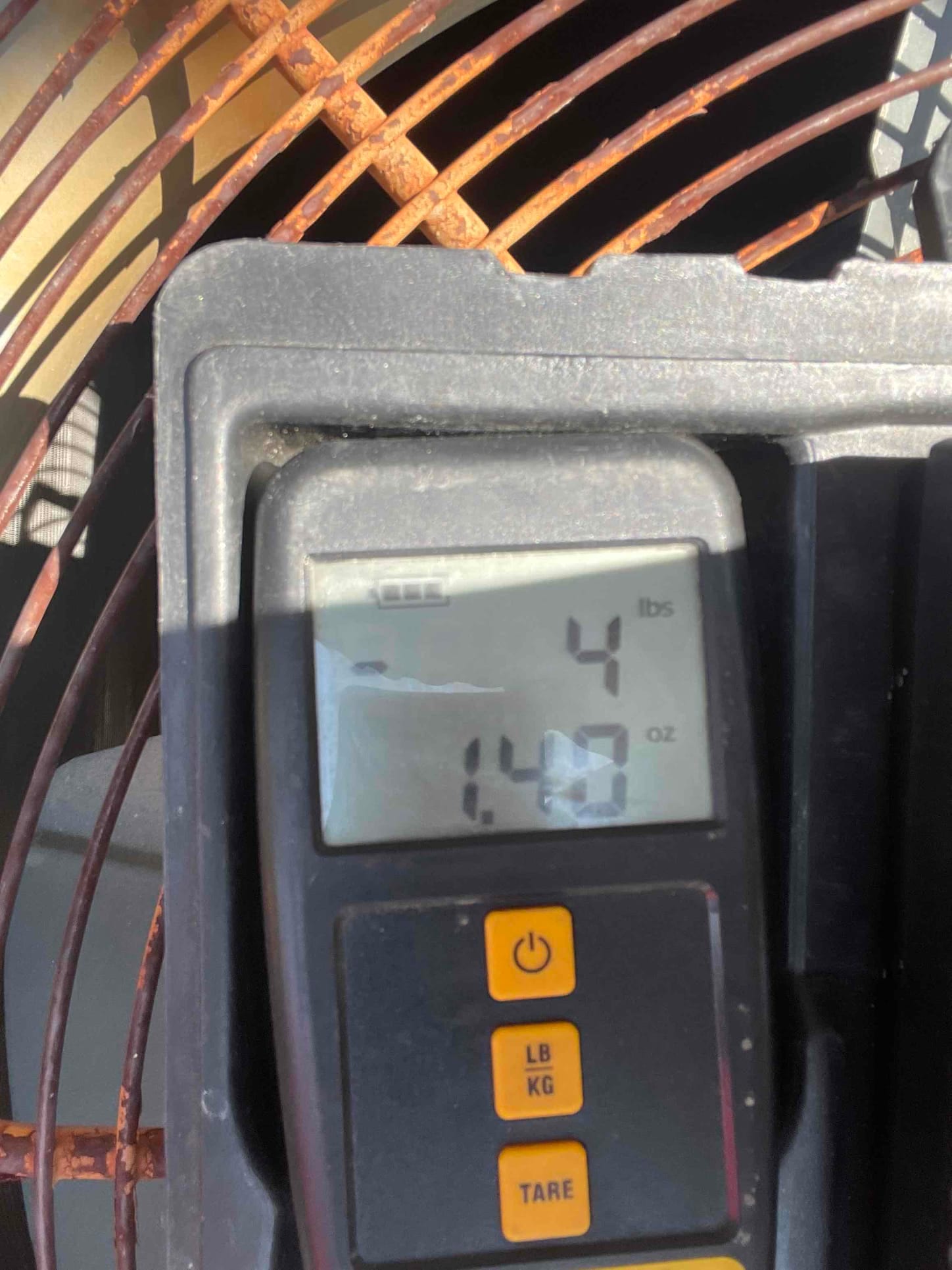 Digital refrigerant scale shows a charge amount of 4 pounds 14 ounces during system commissioning at the outdoor unit.