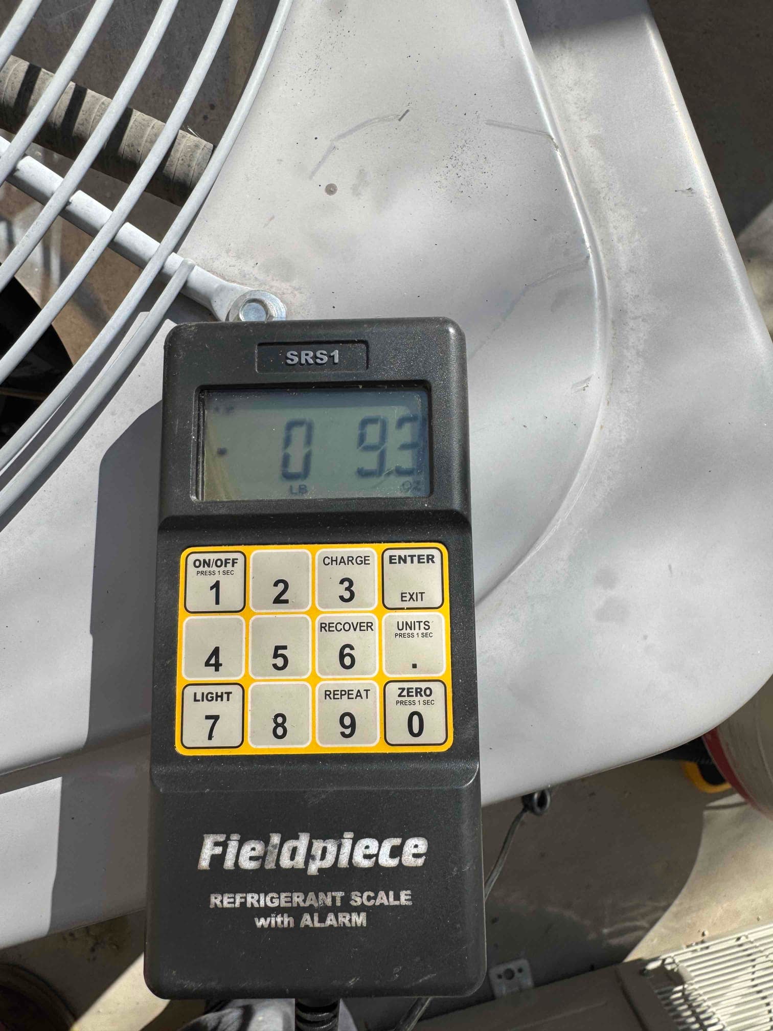 Digital refrigerant scale on top of the outdoor unit shows 0.93 lb during charging setup.