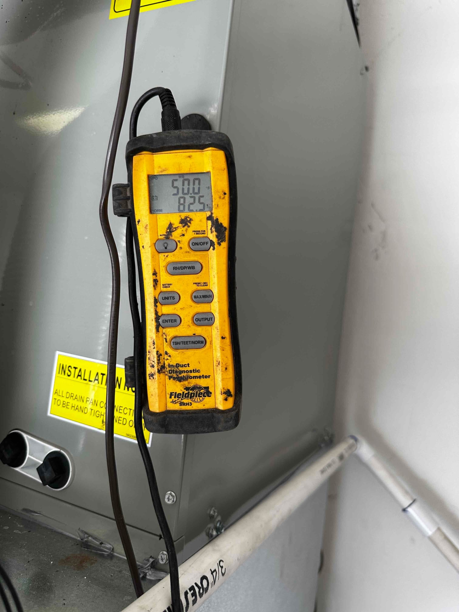 Digital thermometer in the air handler area shows 50.0 degrees on the primary display during supply air check.