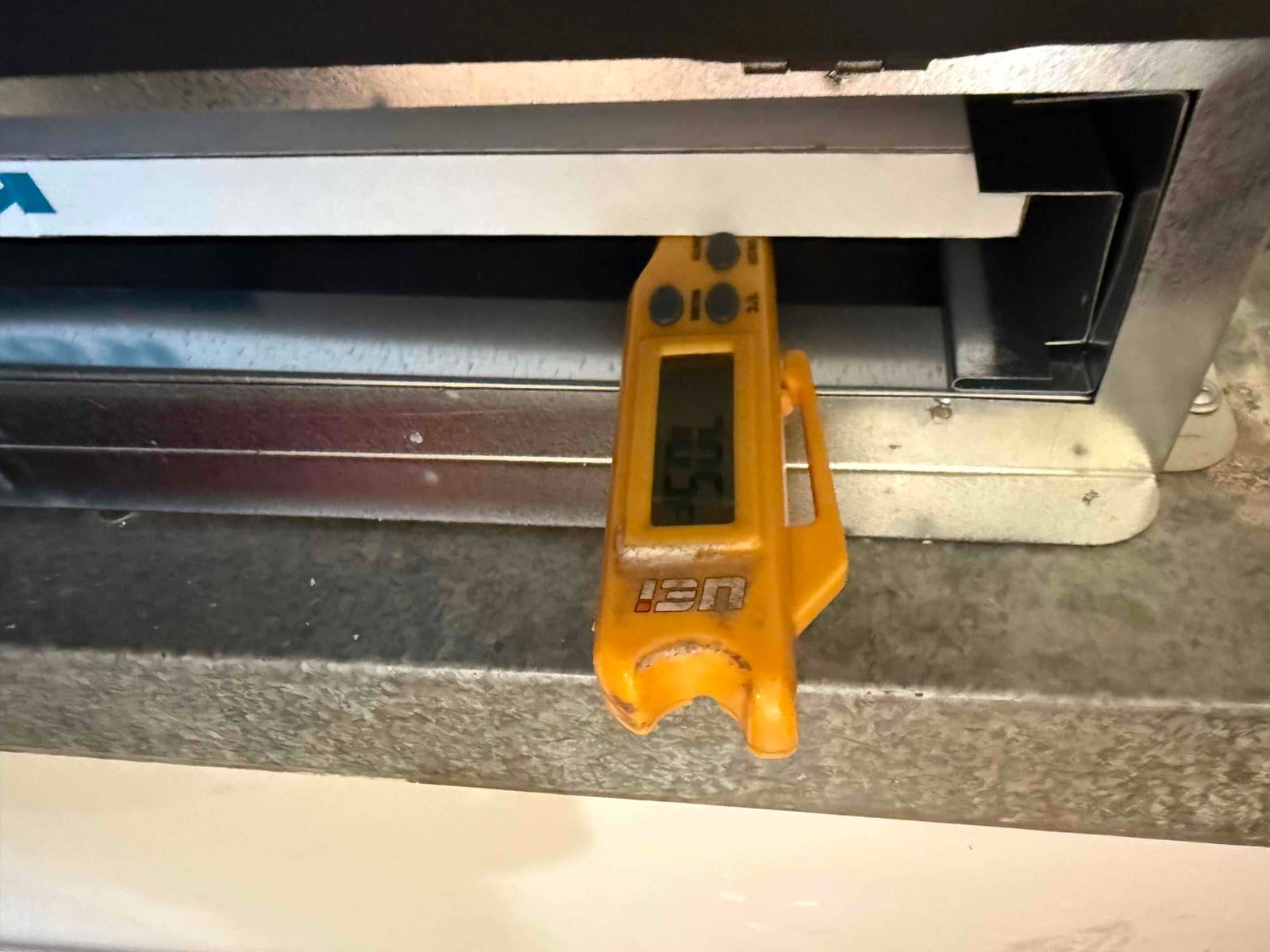 Digital thermometer inserted at a supply register shows 55 degrees Fahrenheit, documenting cooled air leaving the evaporator.