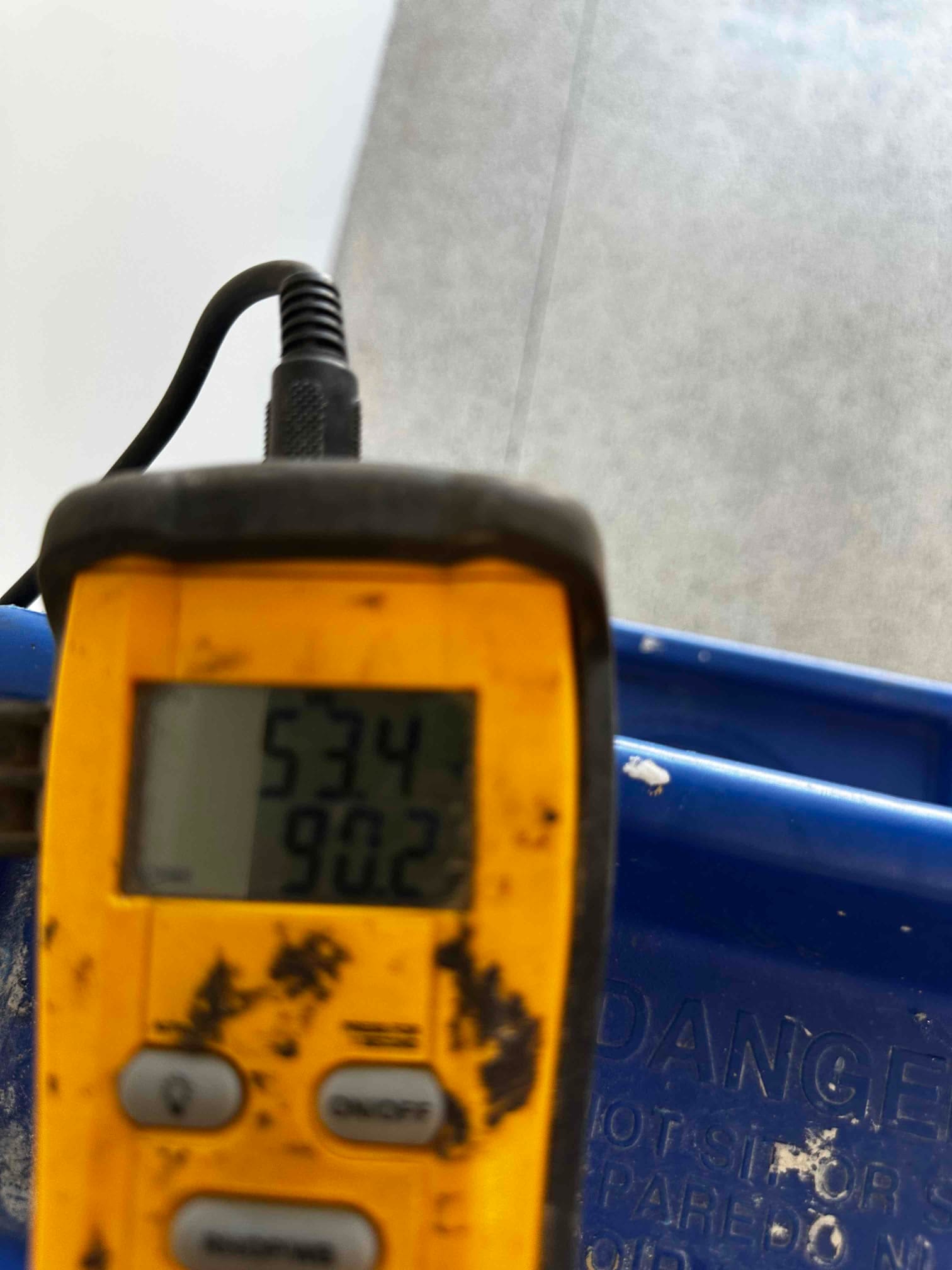 Digital thermometer probe displays 53.4 degrees Fahrenheit, documenting cold supply air temperature from the mini-split.