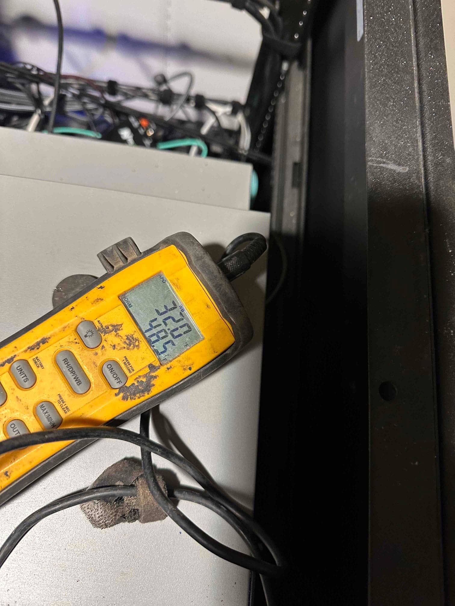 Digital thermometer probe measures air temperature during commissioning, with the display showing a reading in the mid‑70s Fahrenheit.