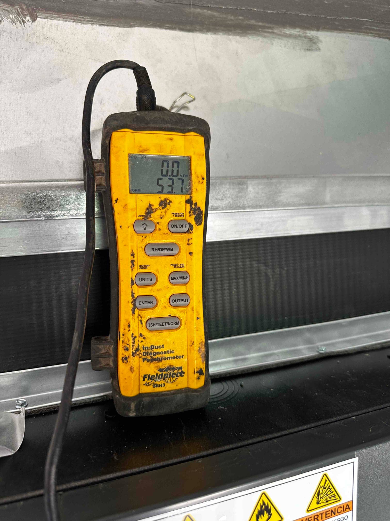Digital thermometer shows 53.7 degrees Fahrenheit while measuring air temperature at the supply near the indoor unit.