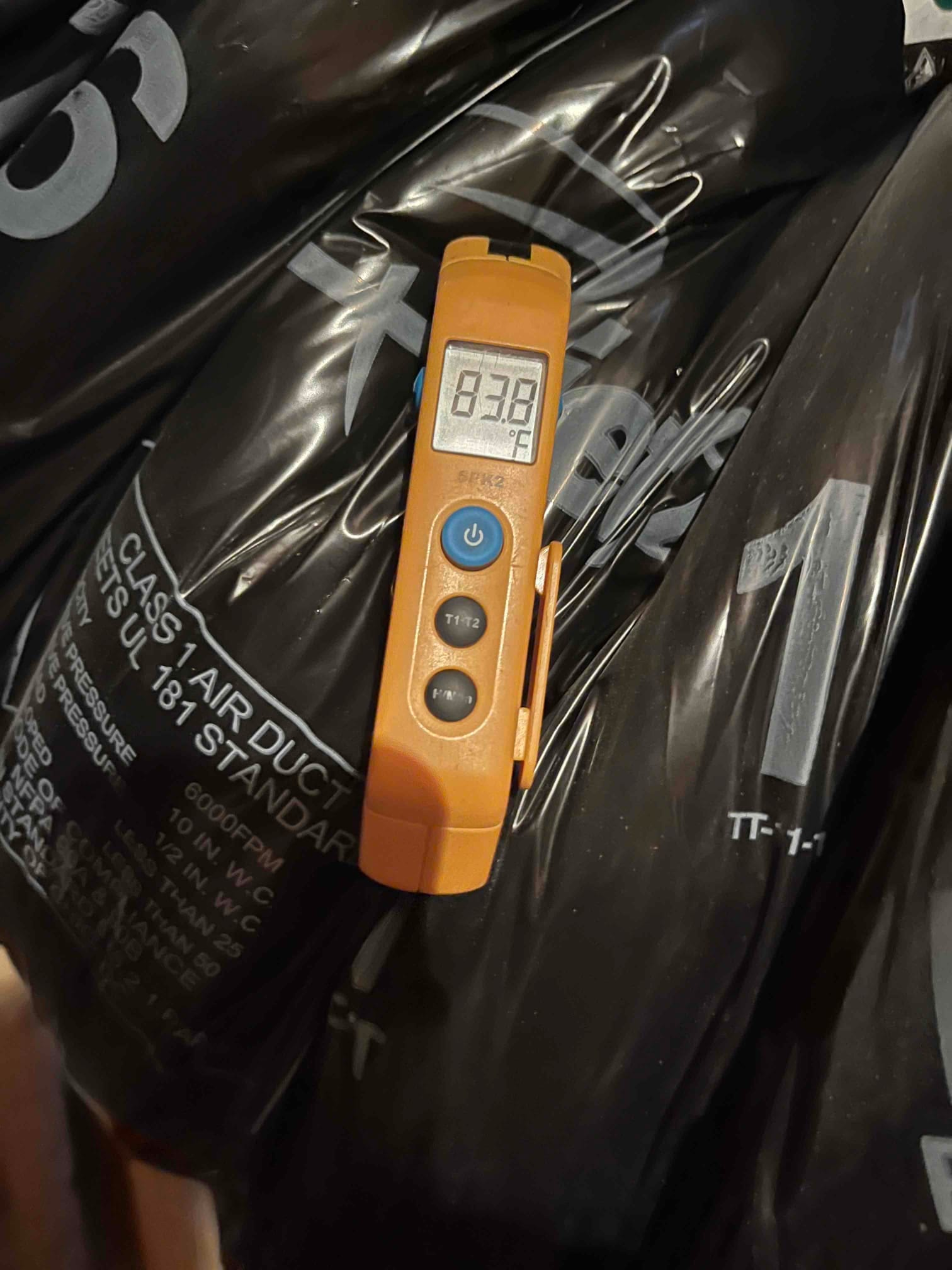 Digital thermometer shows 83.9 °F while measuring surface temperature on insulated flexible air duct.