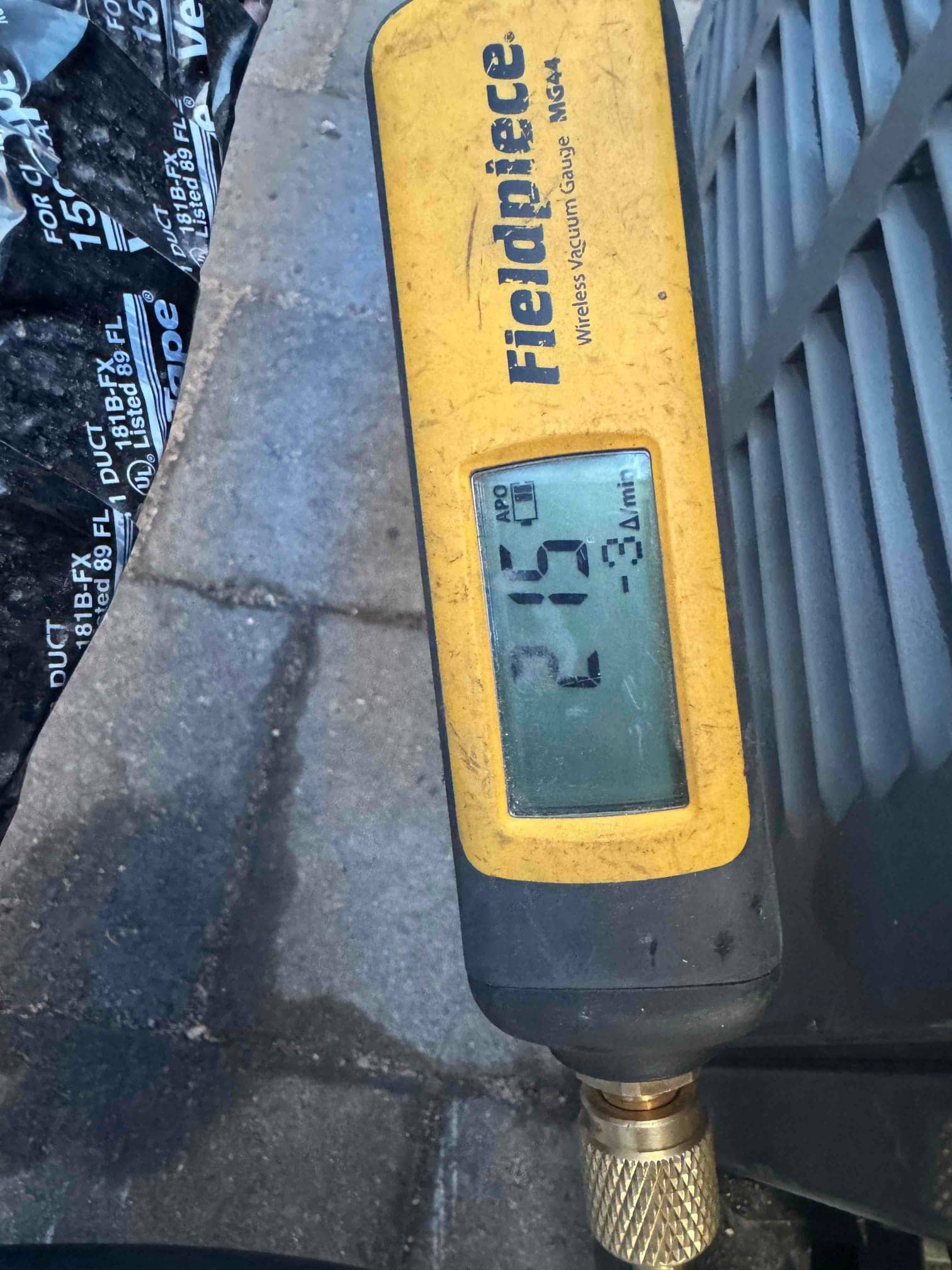 Digital vacuum gauge connected at the outdoor unit displays 219 microns, confirming a deep evacuation before refrigerant charging.