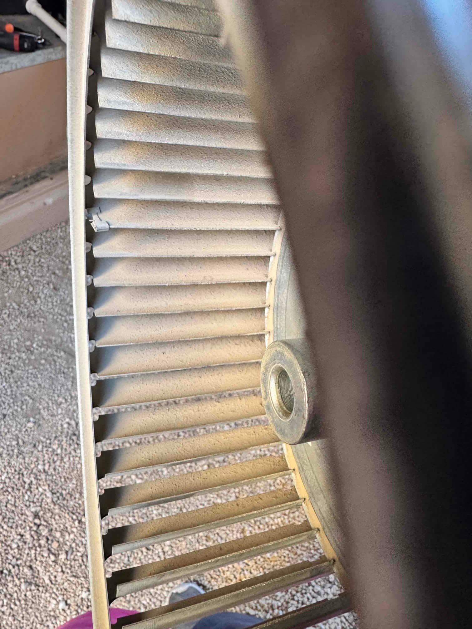 Dirty blower wheel removed from the air handler, showing dust buildup on the fins before cleaning and reinstallation.