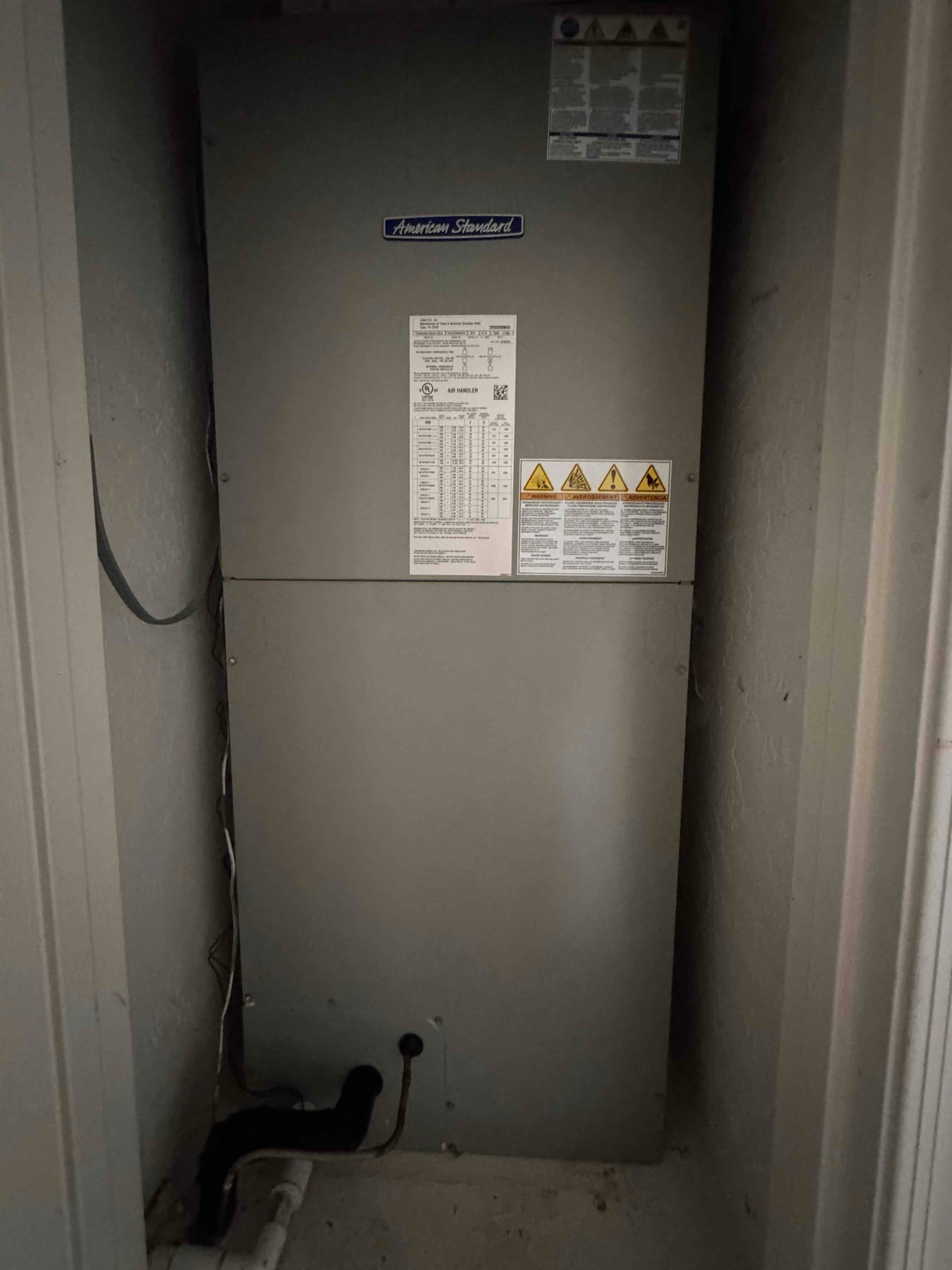 Indoor air handler installed in a closet with condensate drain, insulated suction line, and panels secured after installation.