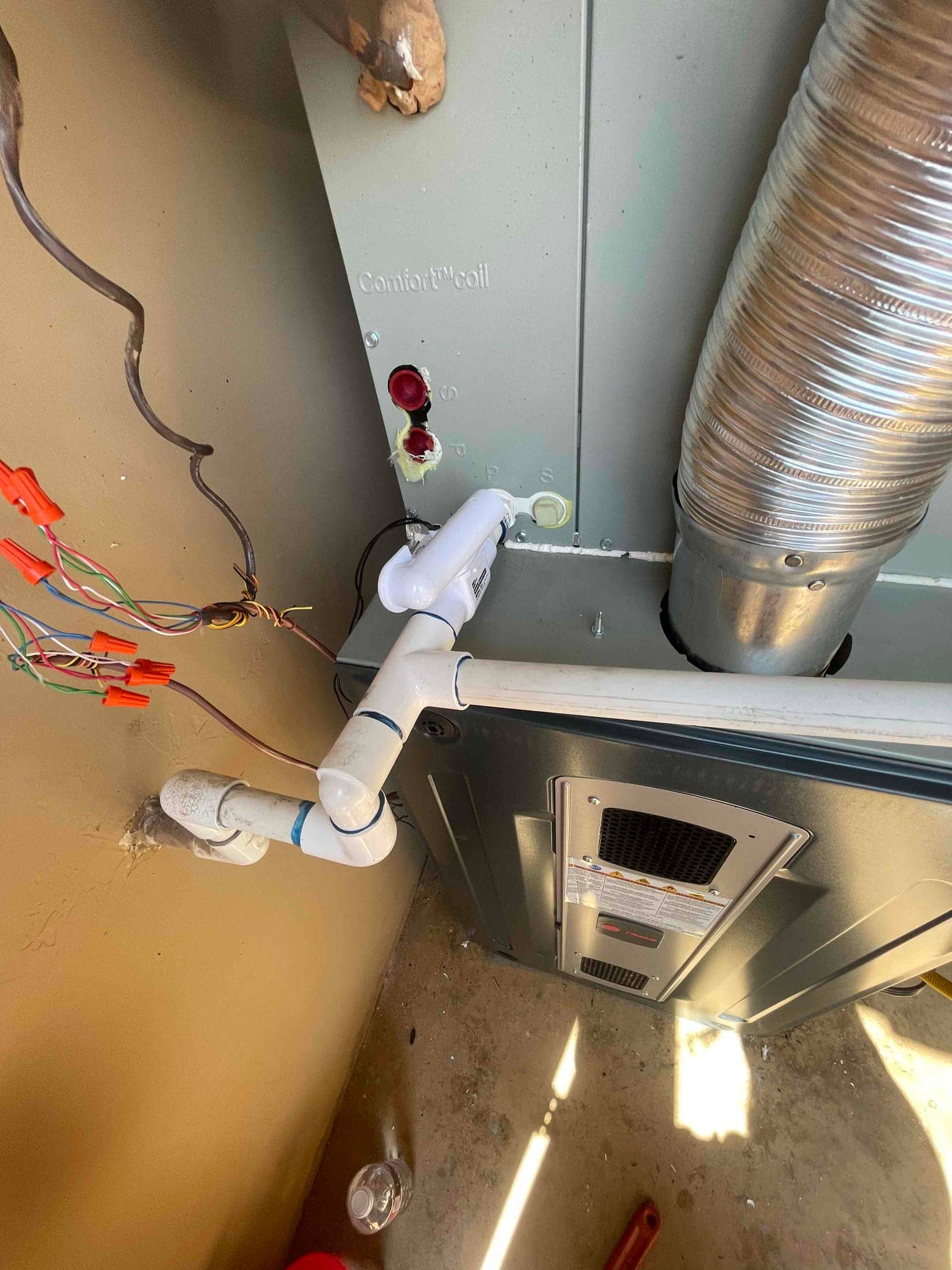 Indoor coil and furnace assembly with newly plumbed condensate drain and wiring connections visible at the installation site.