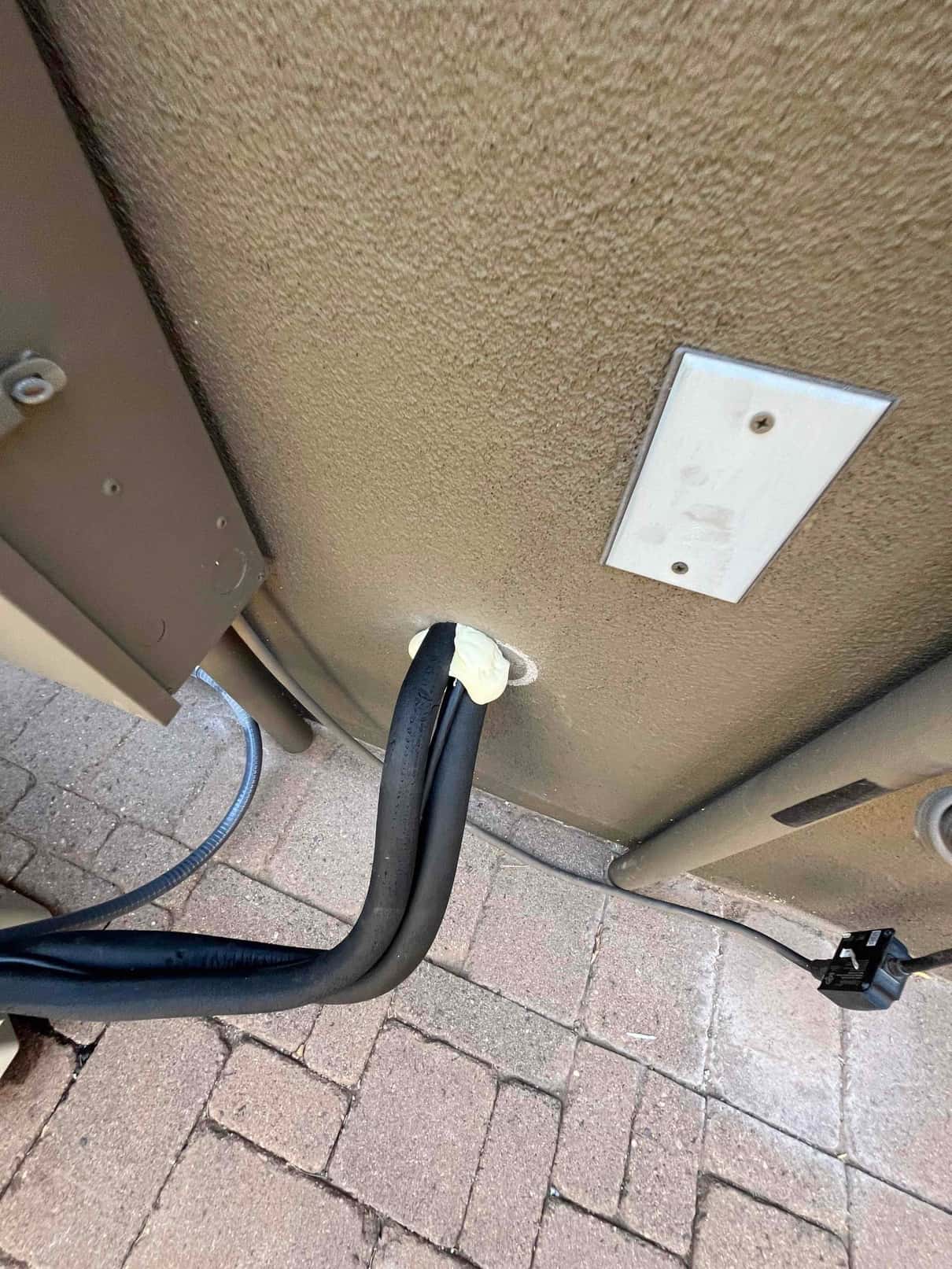 Insulated refrigerant line set neatly routed through the exterior wall penetration, sealed with putty to protect the building envelope.