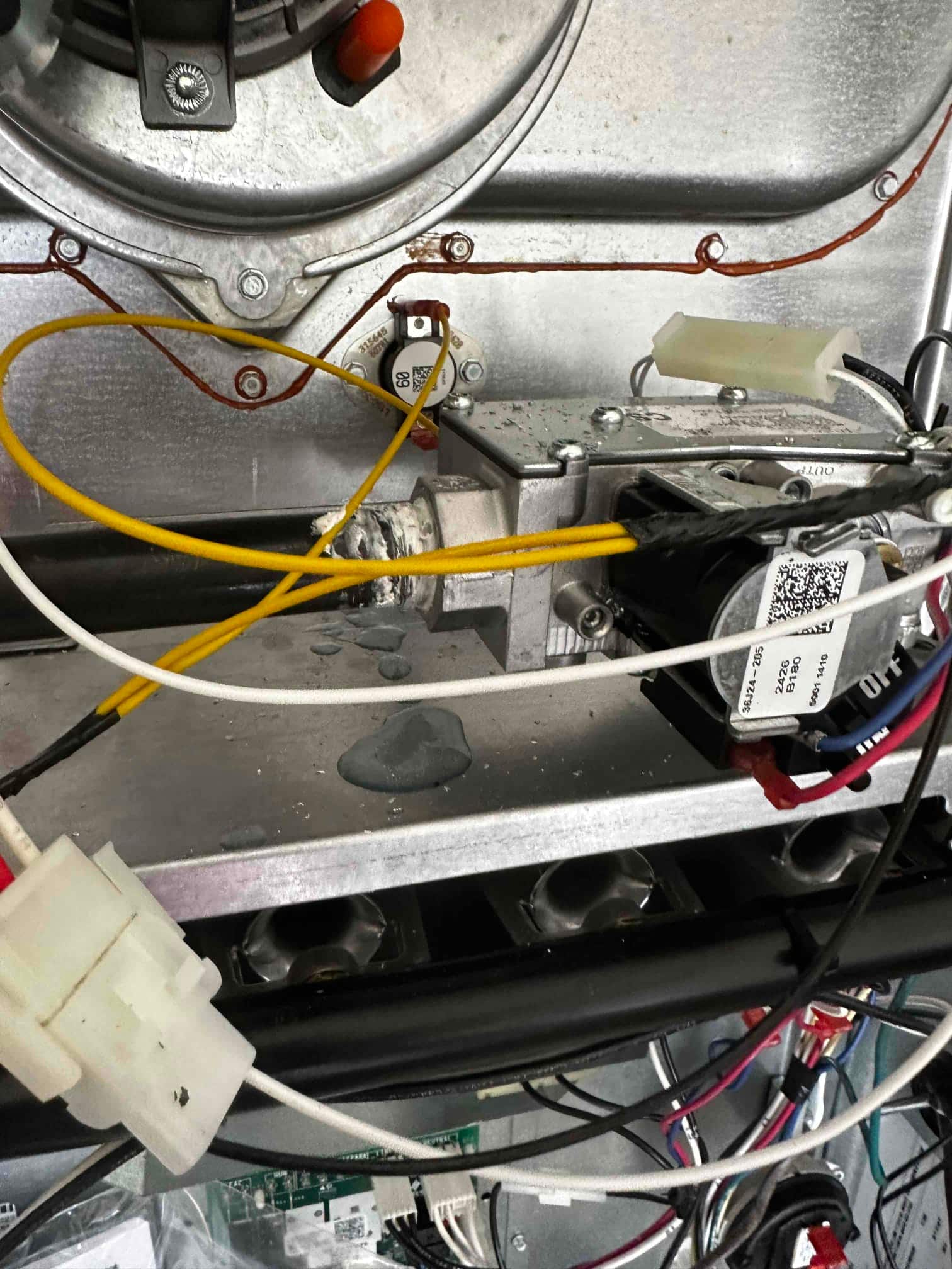 Interior of a gas furnace showing gas valve, wiring harnesses, limit switch, and burner compartment during installation.