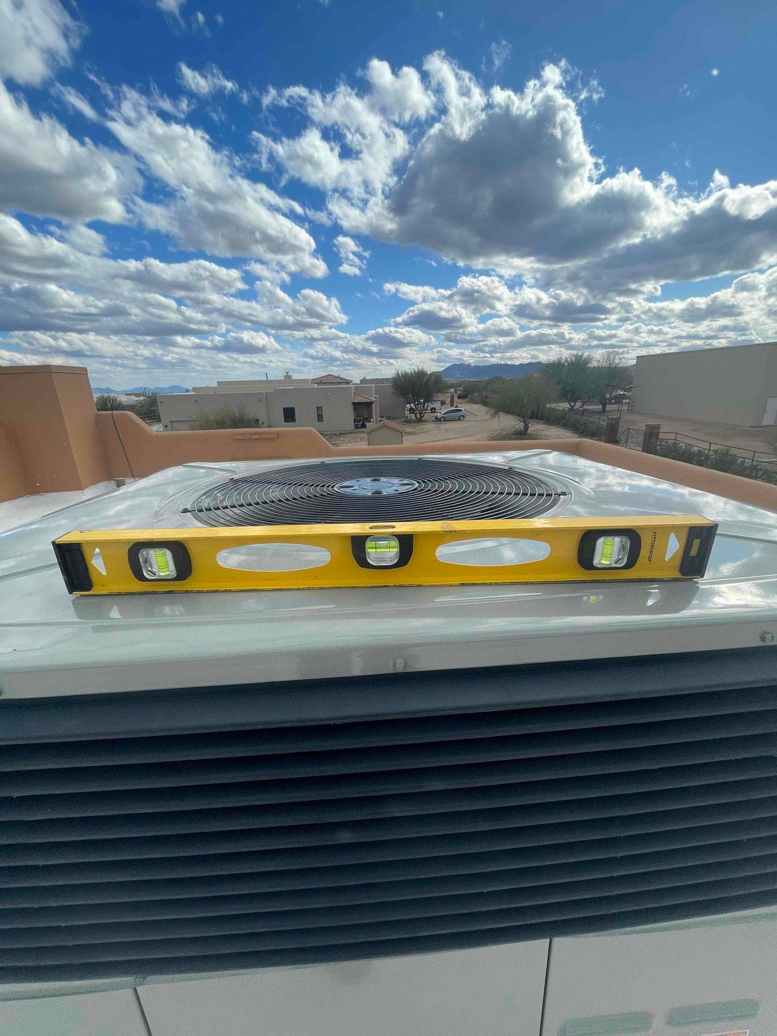 Level placed on top of an outdoor condenser cabinet to verify the unit is set square and level on its pad.