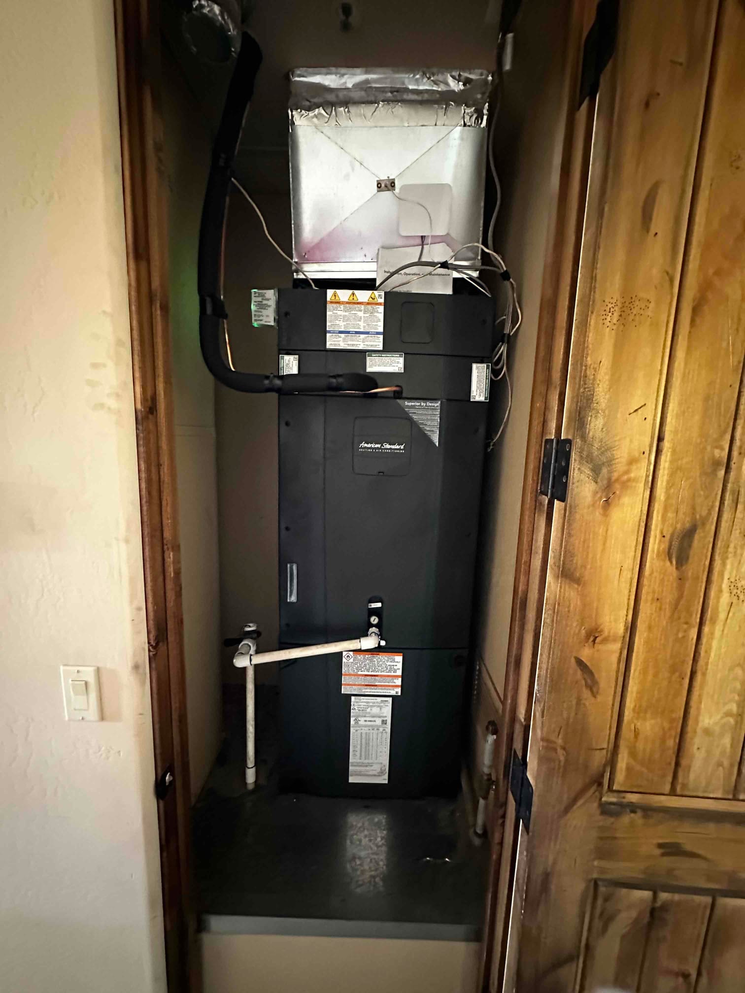 New air handler installed in a closet with insulated suction line, sheet-metal plenum, and PVC condensate drain connections.