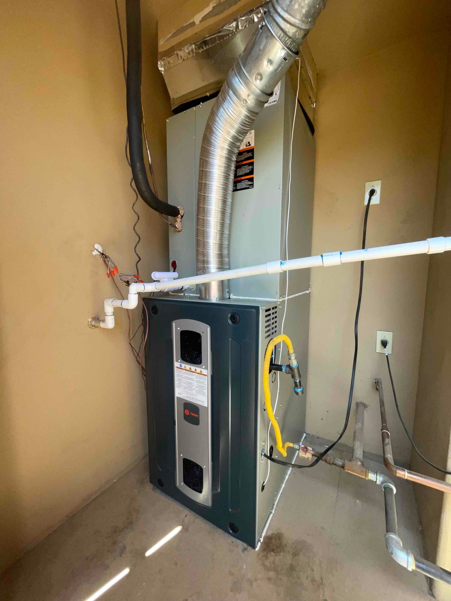 New furnace and evaporator coil installed with venting, condensate drain, gas flex connector, and refrigerant lines routed and sealed.