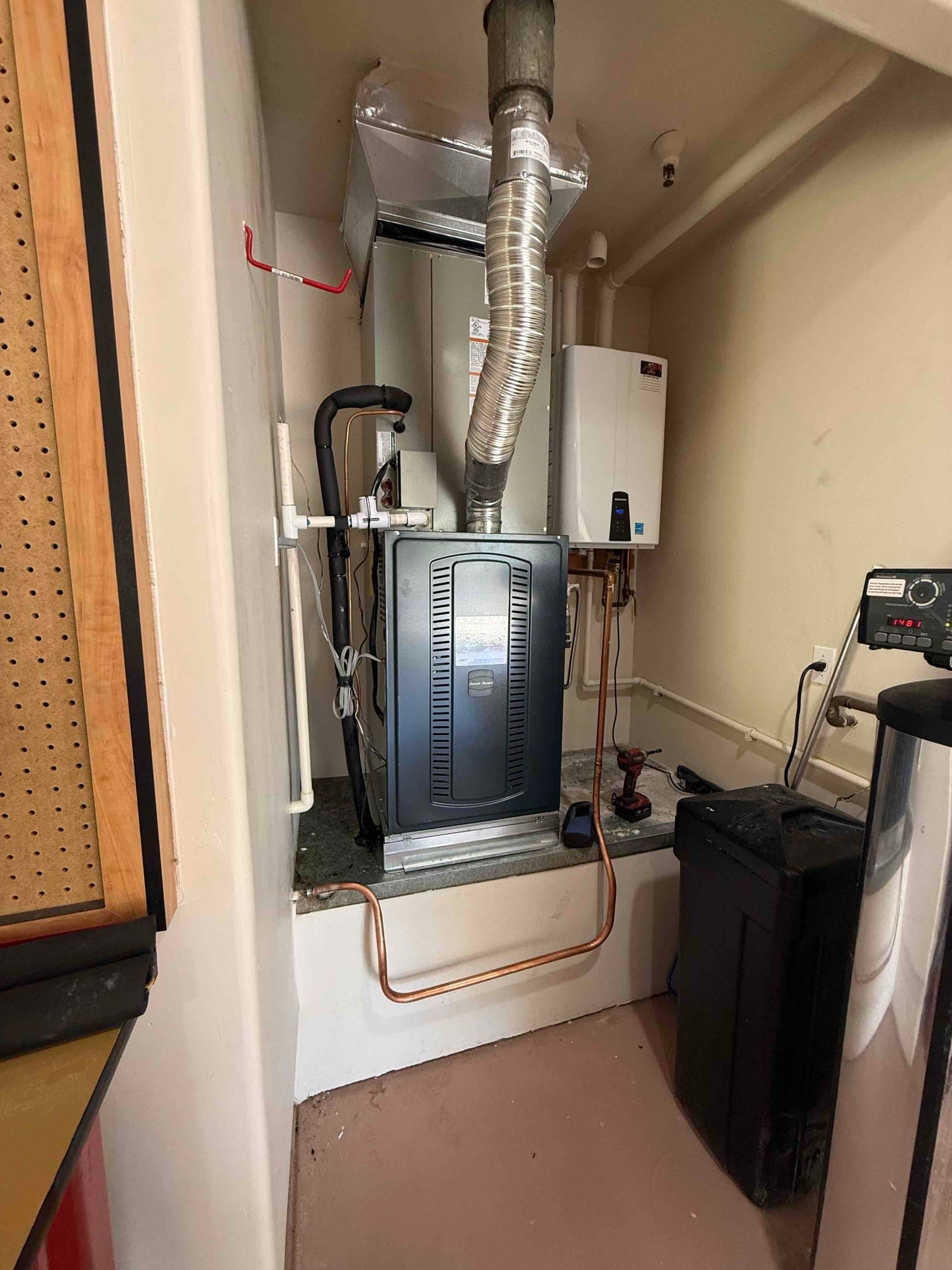 New furnace and evaporator installed with insulated refrigerant lines, condensate drain, and copper line set routing in a utility space.