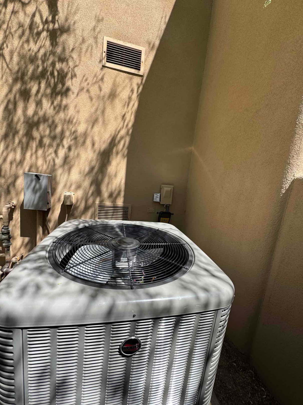 New outdoor condenser installed on pad with electrical disconnect and service whip visible on the exterior wall.