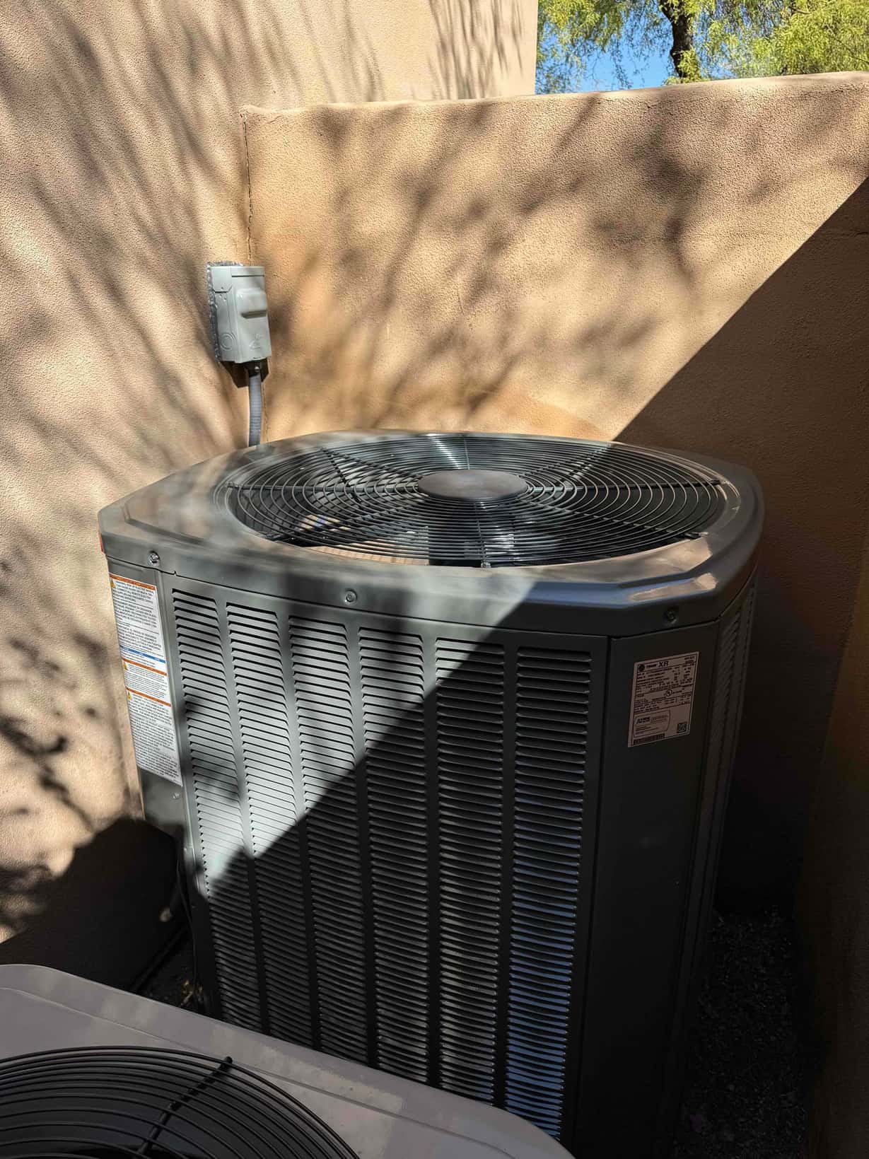 New outdoor condenser installed on pad with nearby weatherproof disconnect and properly spaced ventilation clearance.