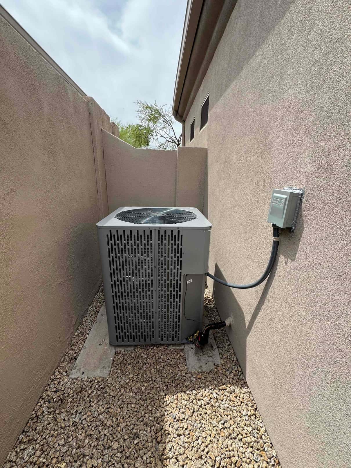 New outdoor condenser set on concrete pads with insulated line set and weatherproof electrical whip connected at the disconnect.