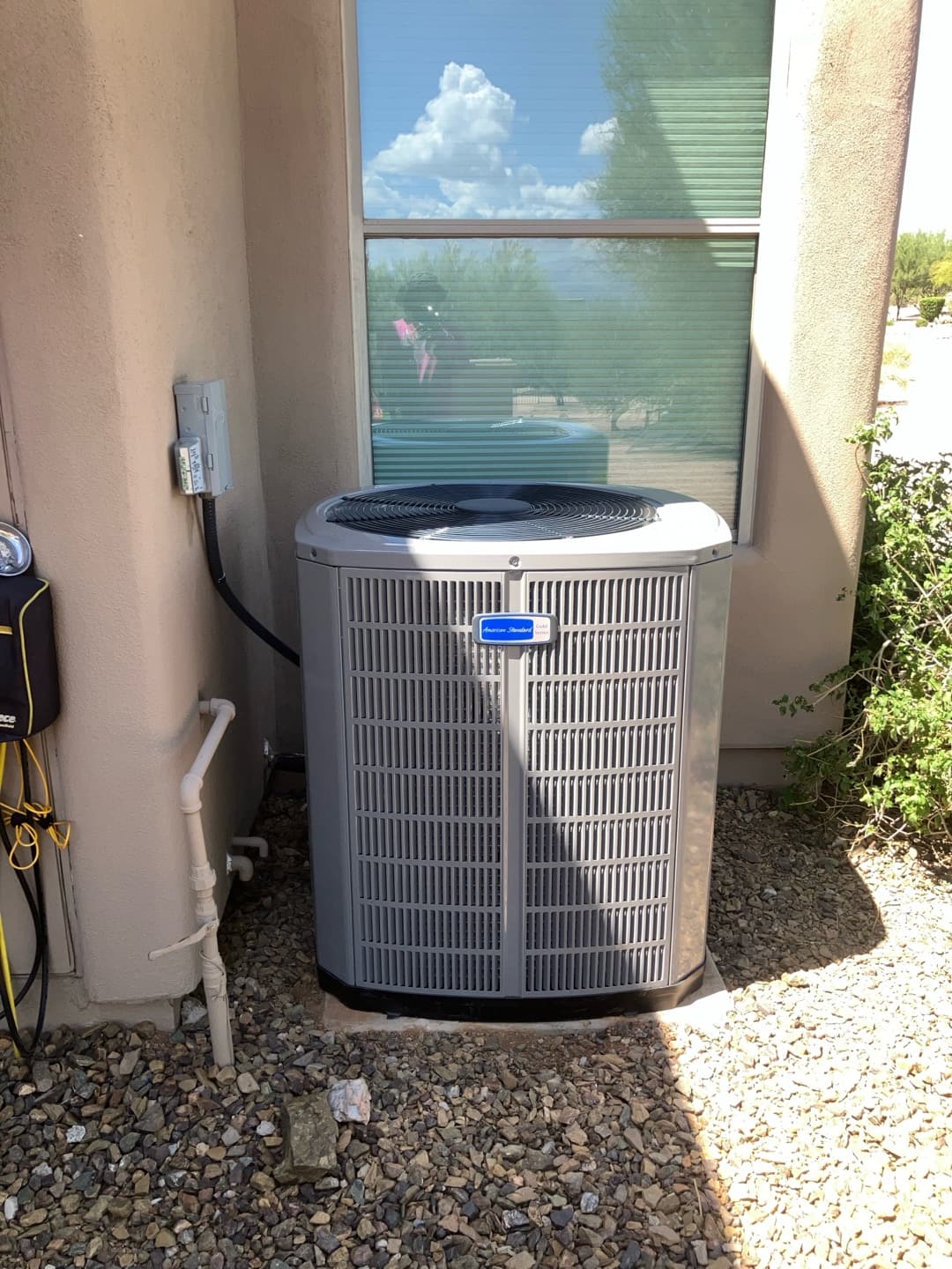 New outdoor condenser set on a level pad with electrical disconnect mounted and insulated line set neatly routed along the wall.