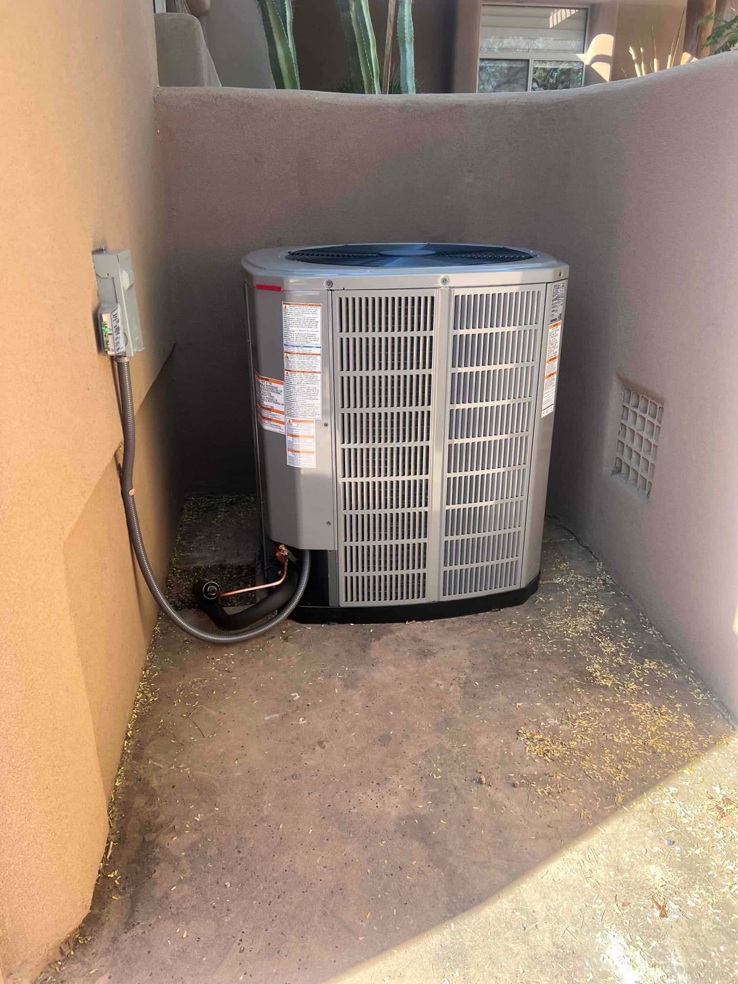 New outdoor condenser set in a recessed area with electrical disconnect and insulated line set neatly connected.