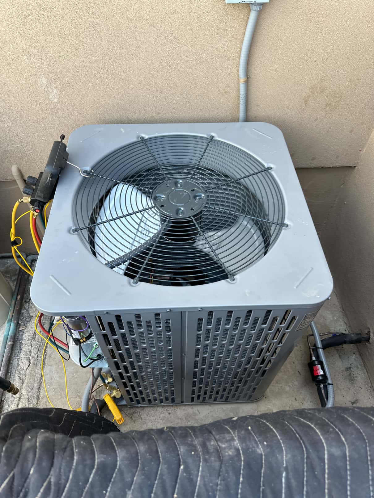 New outdoor condenser set and wired at the service disconnect, with refrigerant lines, whip, and filter-drier installed.