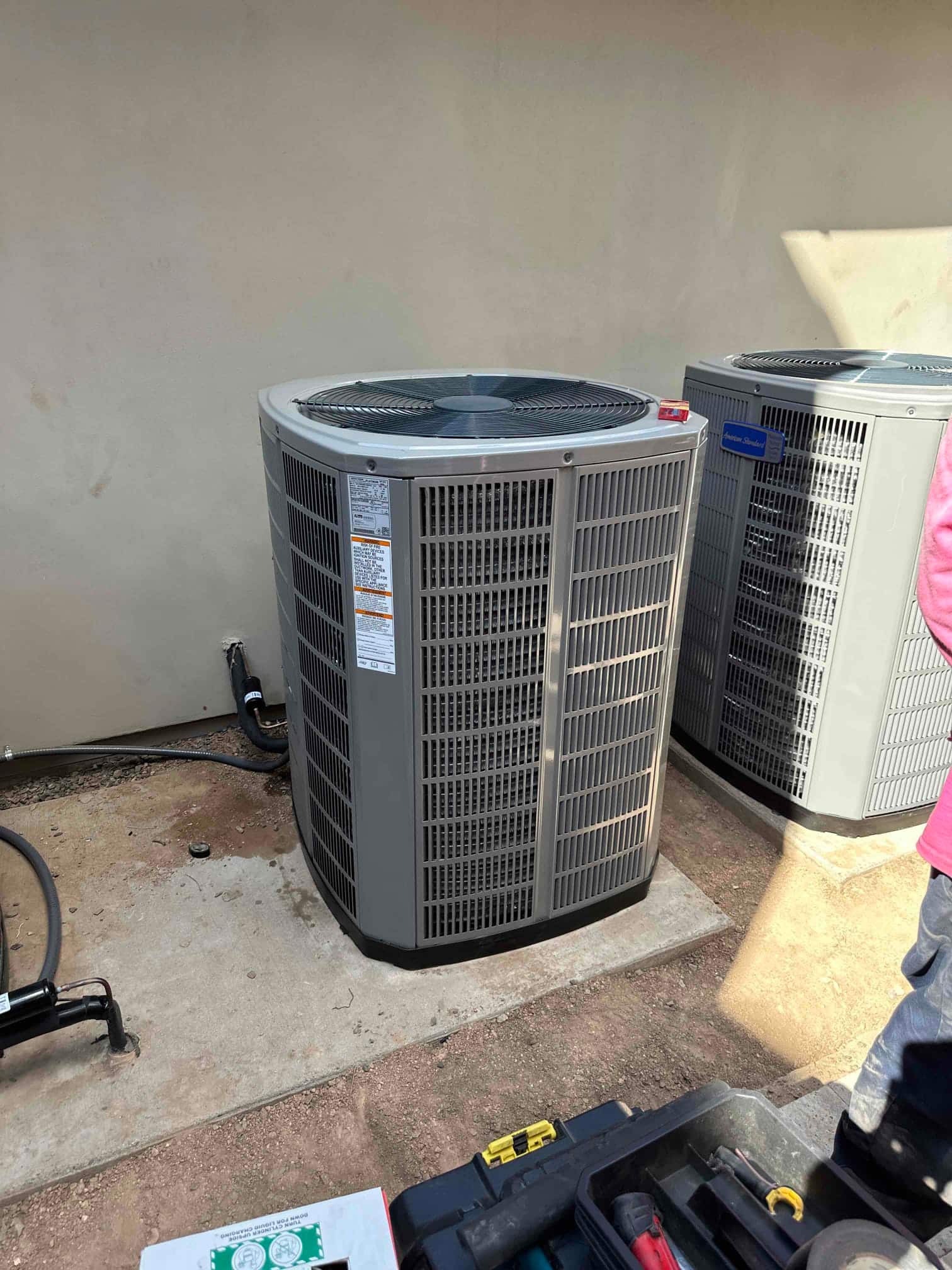New outdoor condensers set on level pads with insulated refrigerant lines and electrical whip routed to the wall.