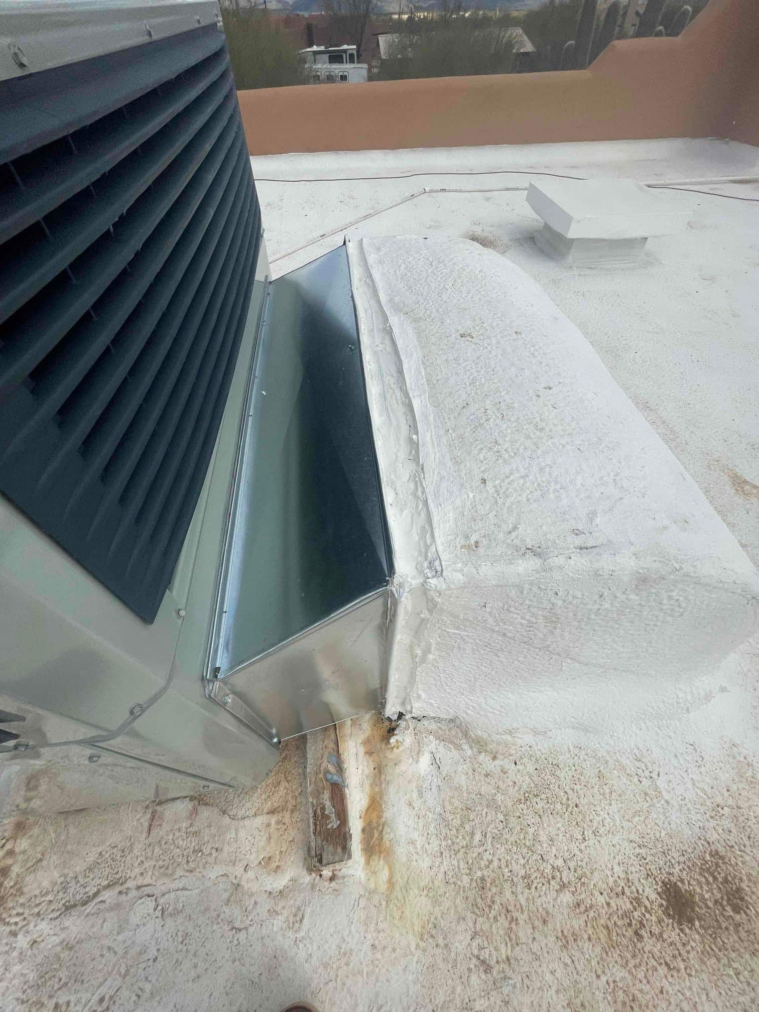 New rooftop package unit with fabricated sheet-metal supply/return transition sealed to the roof curb and coated for weatherproofing.