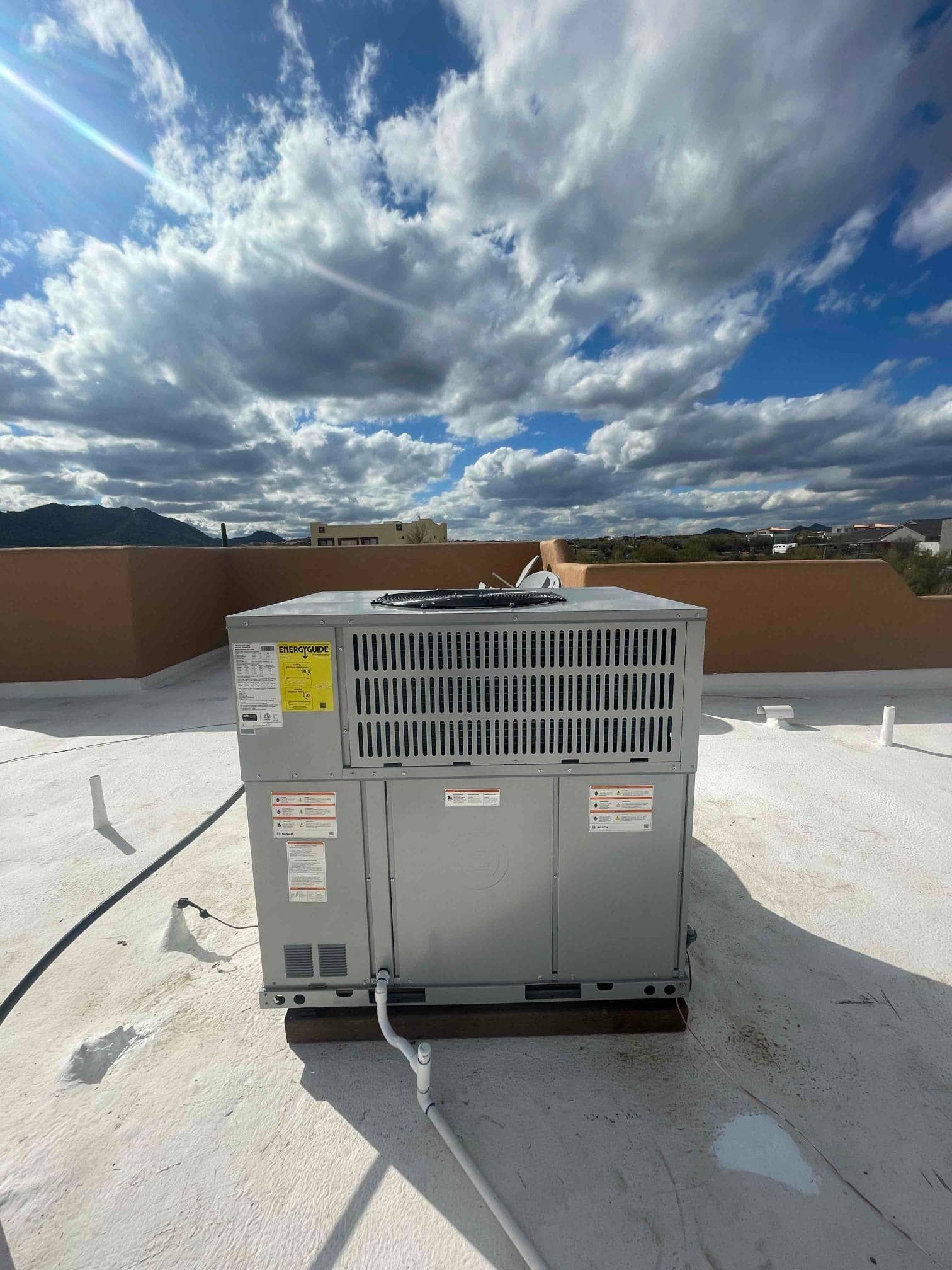 New rooftop packaged HVAC unit installed on curb with condensate drain connected and sealed roof penetrations visible.