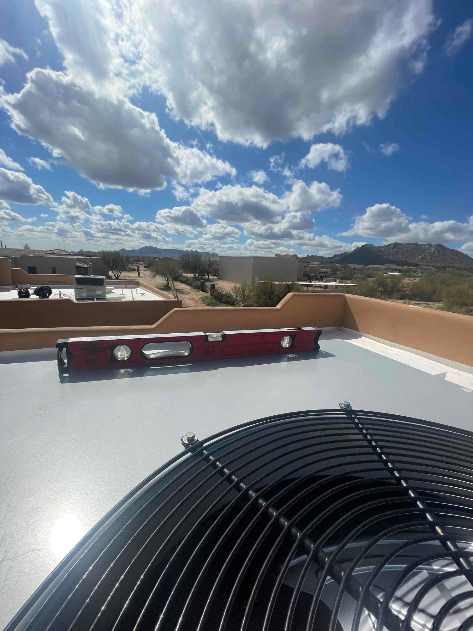 Outdoor condenser set on a rooftop pad, with a level placed on top to verify proper, level installation.