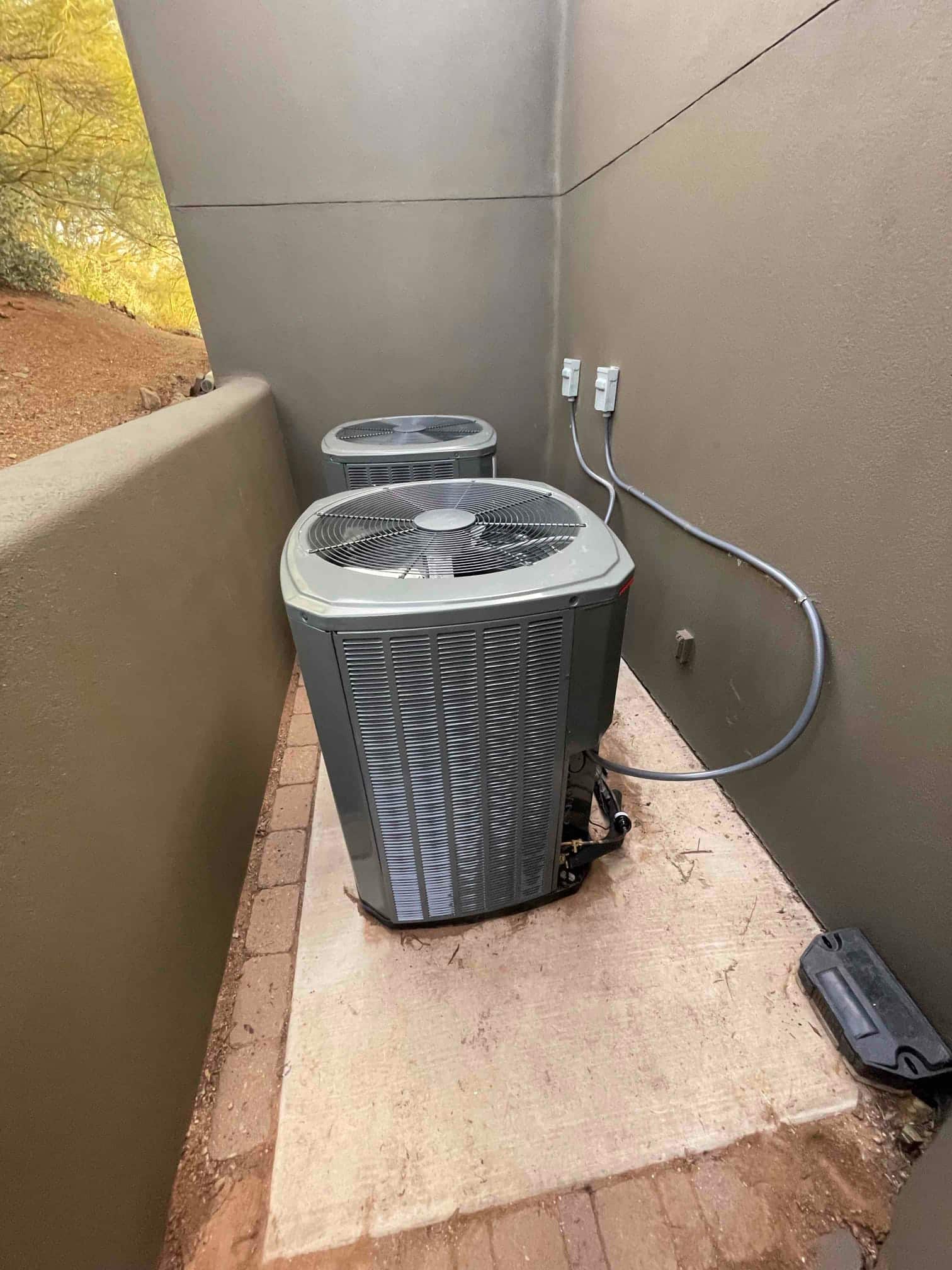 Two outdoor condenser units installed on a concrete pad with weatherproof disconnects and properly routed electrical conduits.
