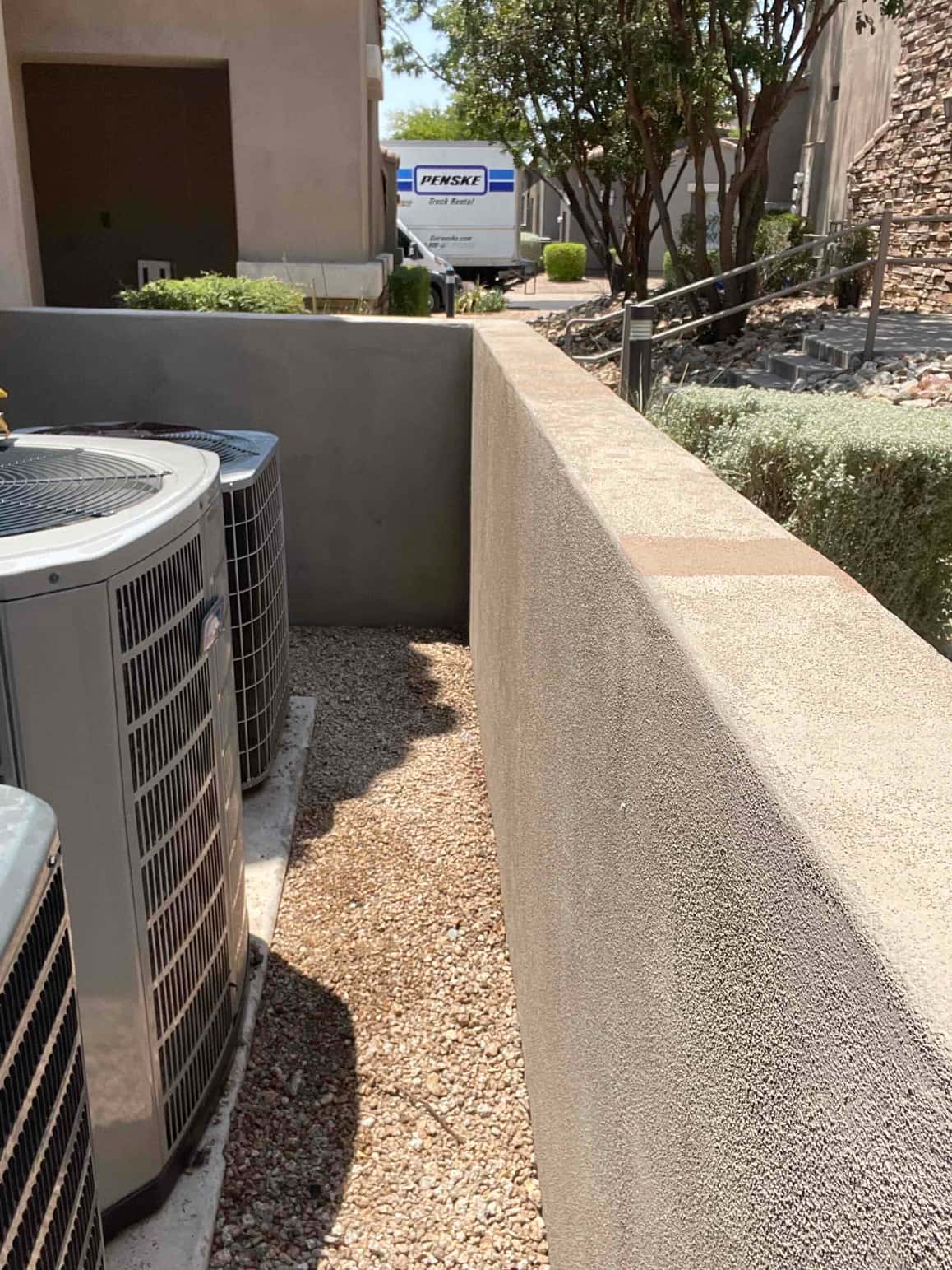 Outdoor condensers installed on a level pad in a side yard service corridor with proper clearances around the units.