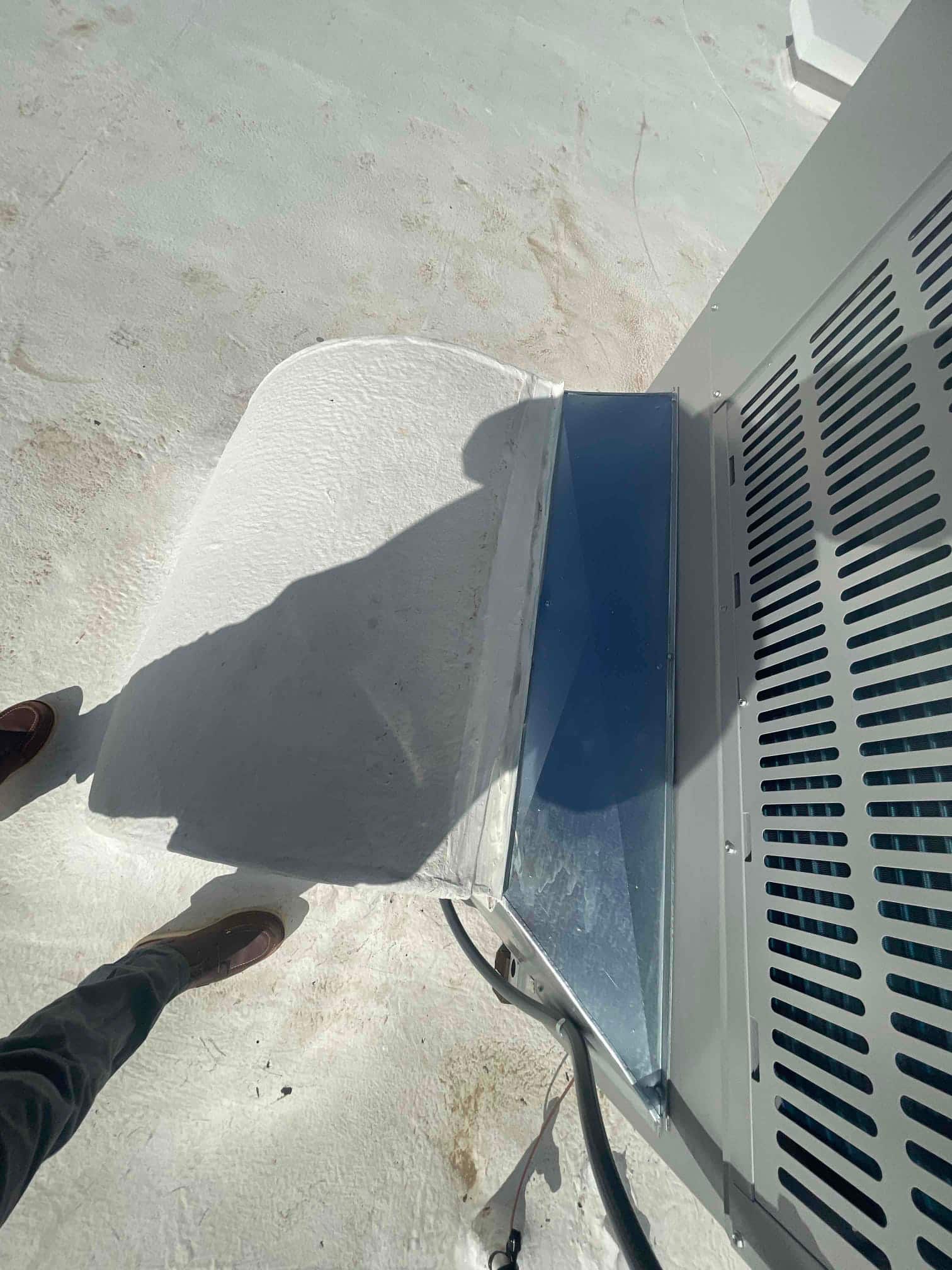 Outdoor heat pump set on a roof with sealed curb and metal curb adapter, electrical whip and conduit connected.