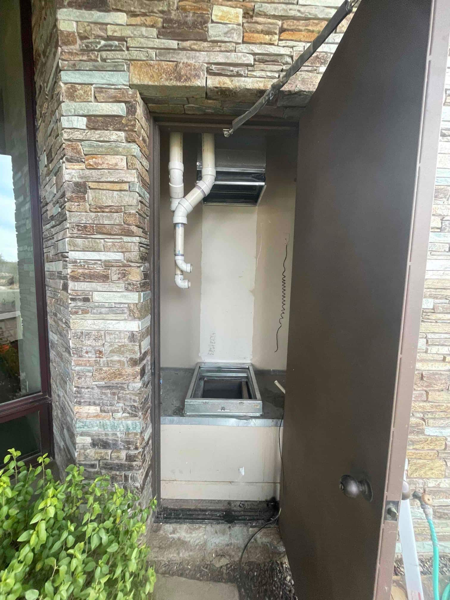 Outdoor mechanical closet prepped for new furnace installation with vent piping, return opening, and sheet metal base in place.