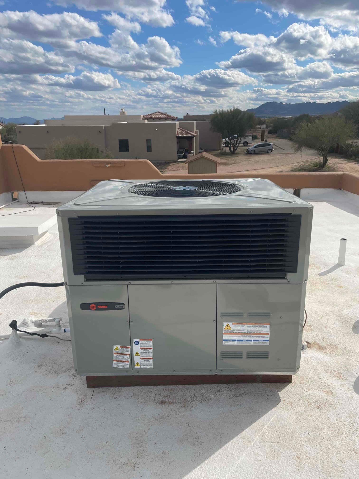 Rooftop packaged HVAC unit installed on a raised platform with sealed line connections and protective grilles visible.