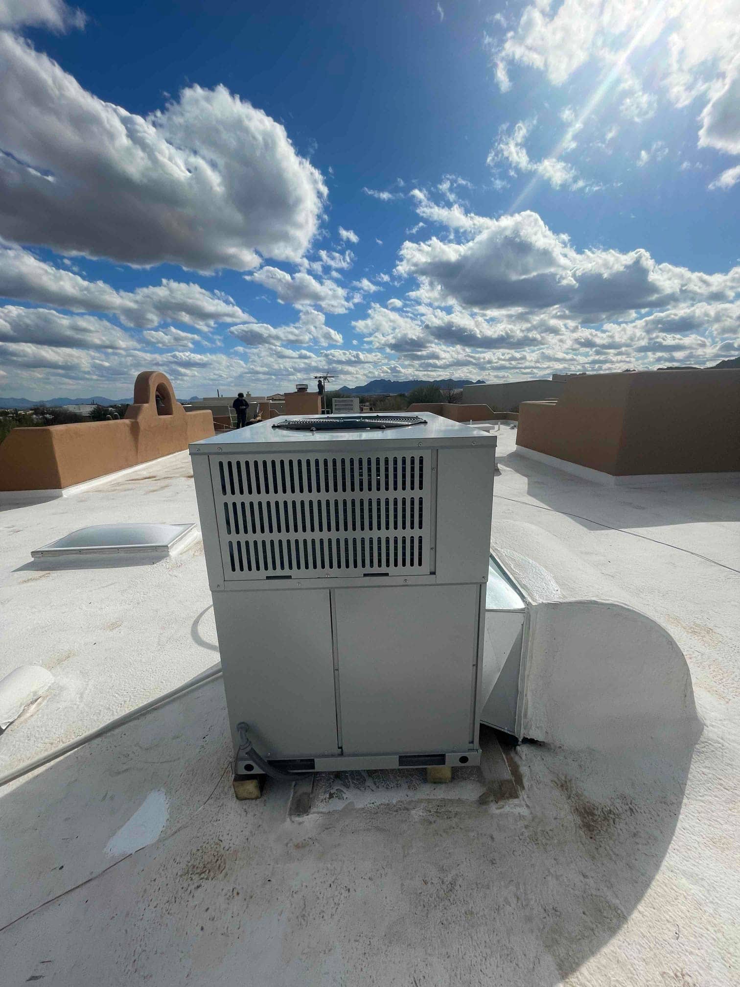 Rooftop packaged HVAC unit set on blocks with sealed duct connection and weatherproof roof surface visible around the installation.