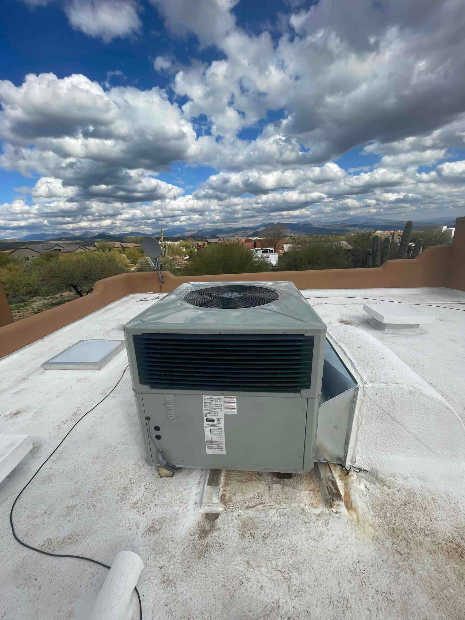 Rooftop packaged HVAC unit set on supports with sealed curb and connected duct transition on a flat roof.