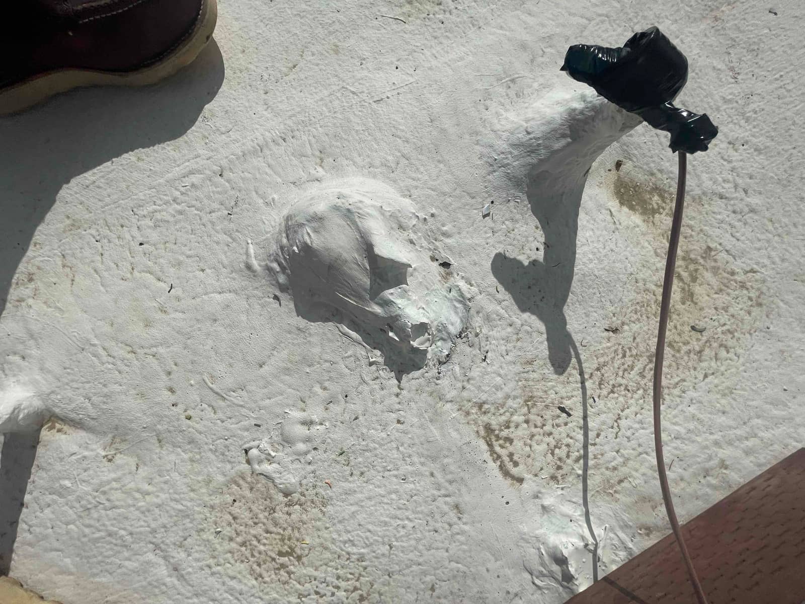 Sealed roof penetration with mastic around line set entry, showing neatly secured cable and surrounding roof coating.