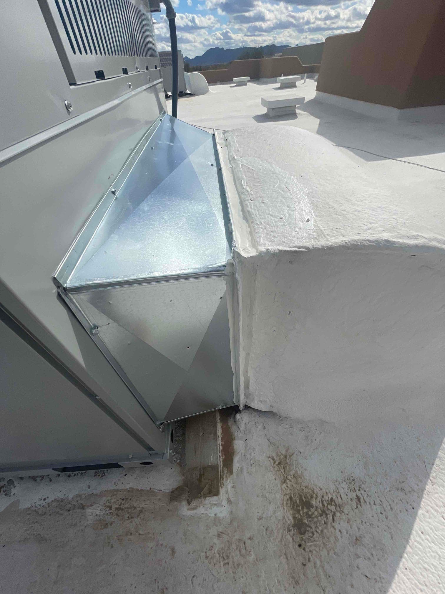 Sheet-metal curb transition sealed to a rooftop package unit, showing clean flashing and weatherproofed roof penetration.