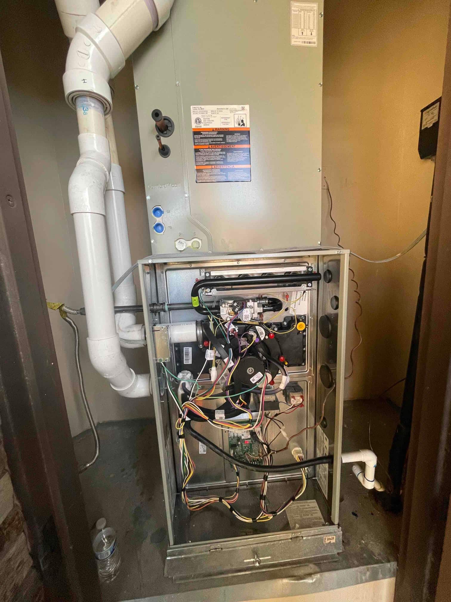 Two-stage gas furnace installed with PVC intake and exhaust, condensate drain, and control wiring exposed during commissioning.