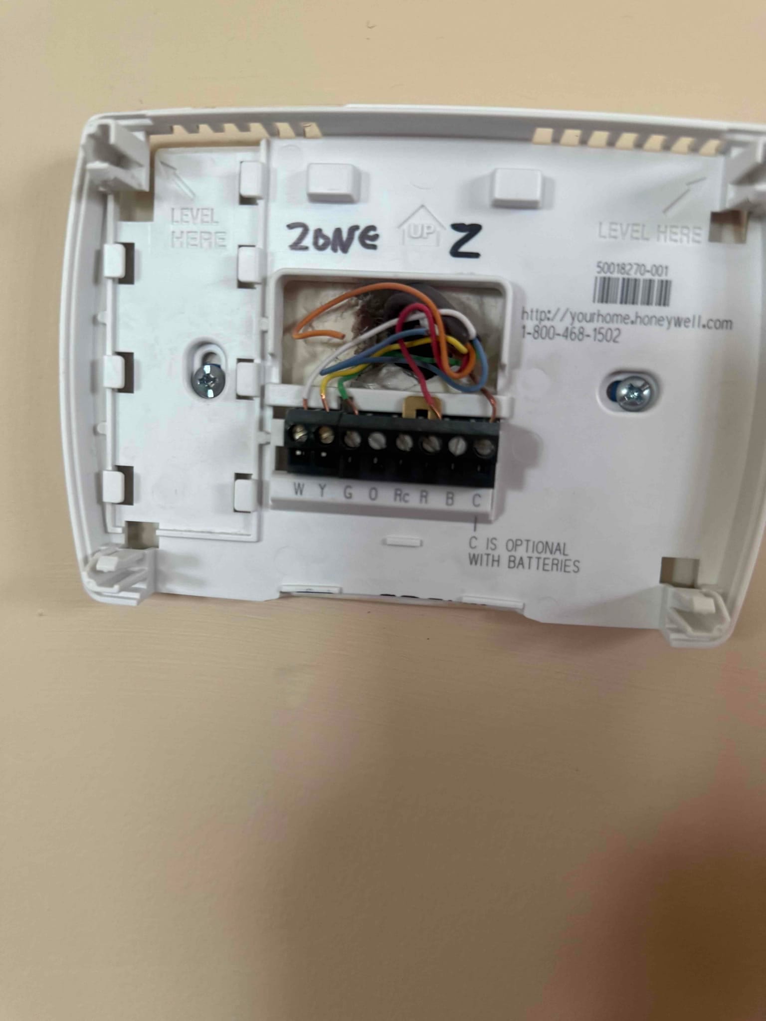 Thermostat sub-base mounted on wall showing connected control wiring to W, Y, G, O/B, R, and C terminals.