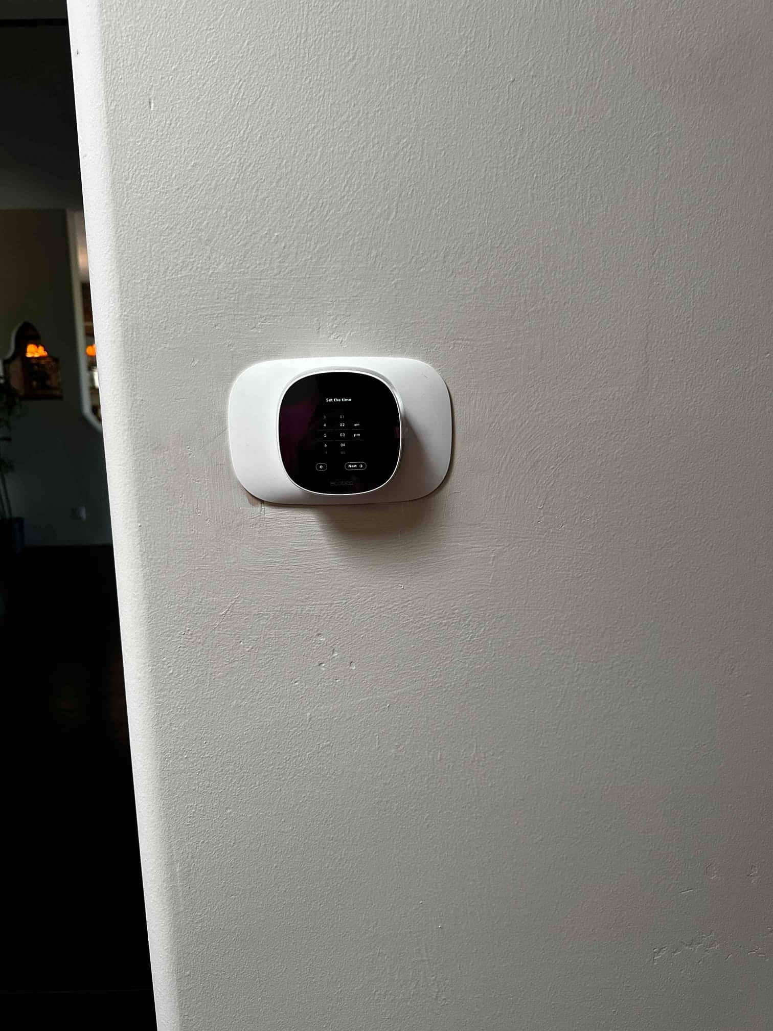 Wall-mounted smart thermostat installed and powered on, displaying setup screen as part of the new HVAC system installation.