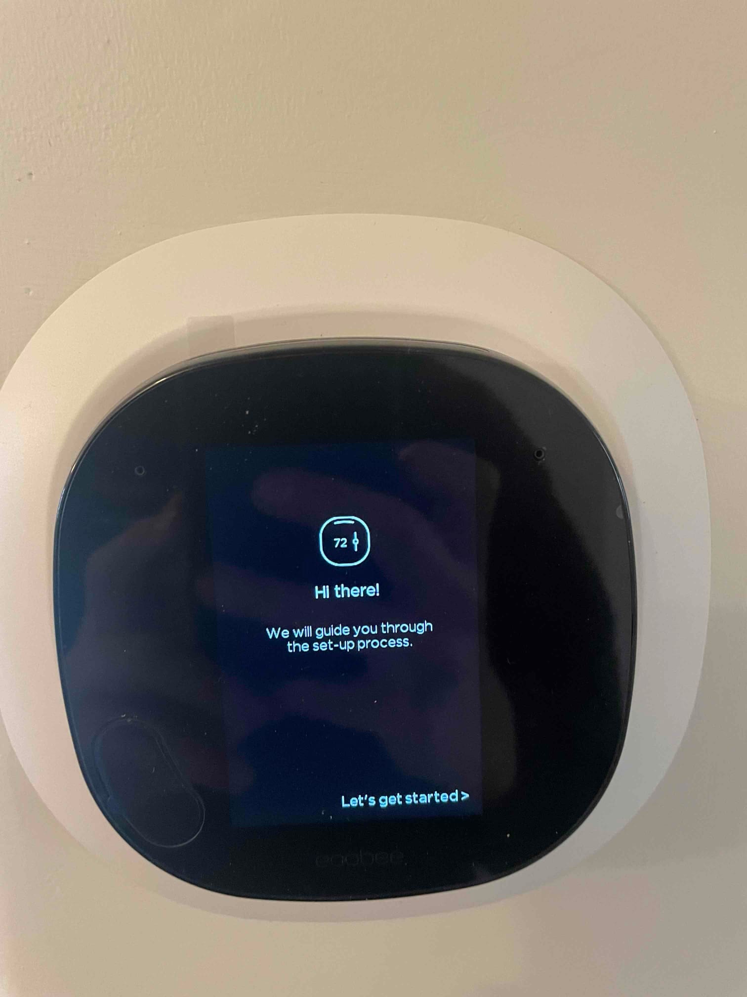 Wall-mounted smart thermostat powers on and begins guided setup after installation.