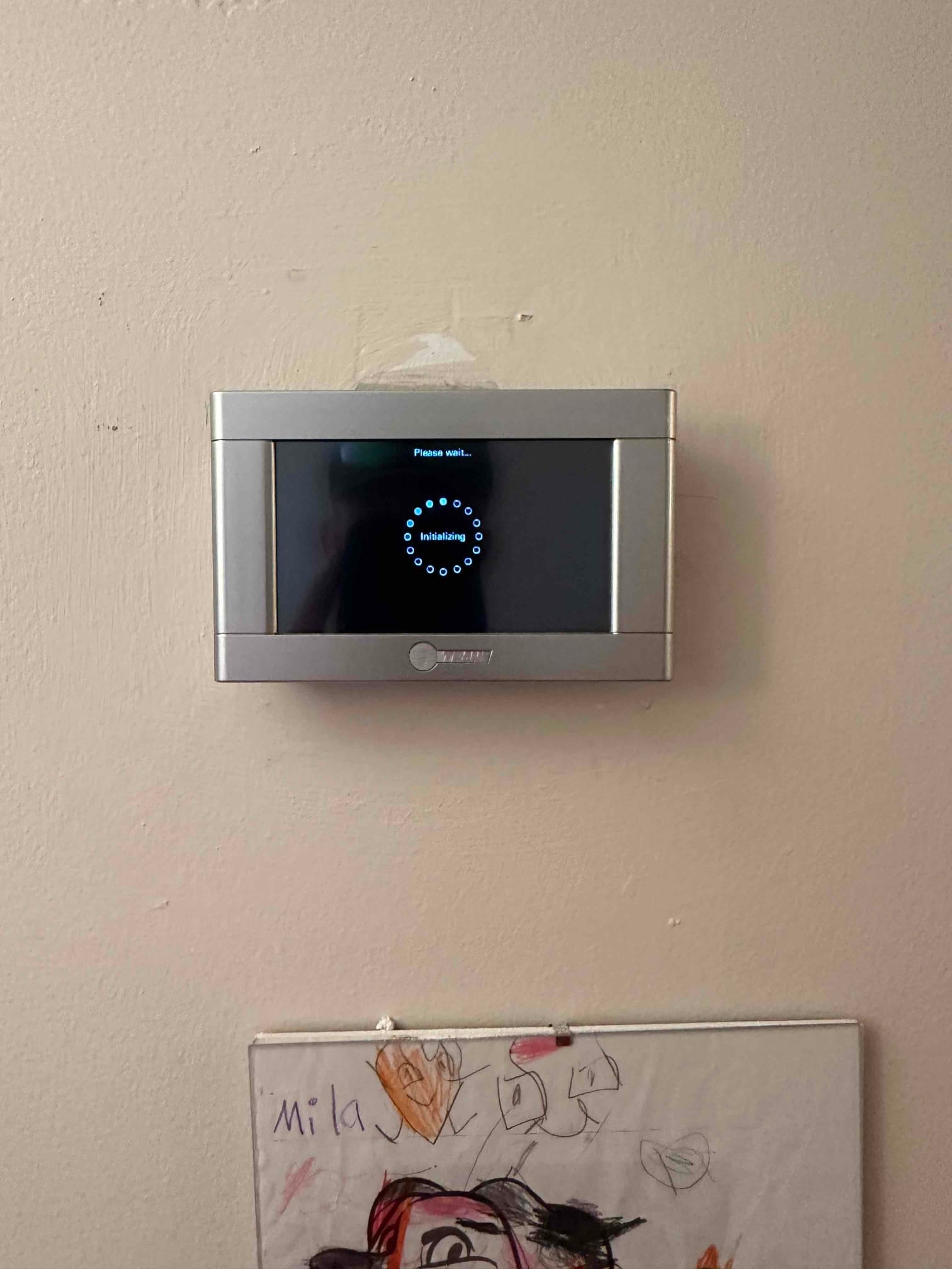Wall-mounted thermostat powers up with an initializing message during setup after the new HVAC system installation.