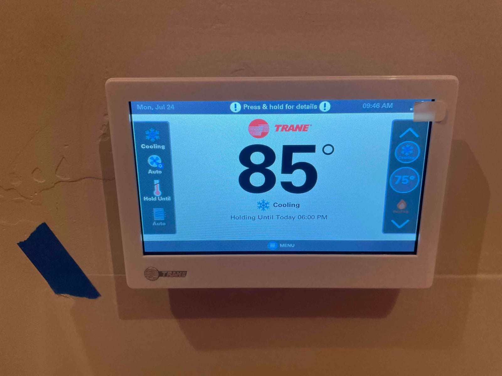 Wall-mounted touchscreen thermostat displays cooling mode with a current indoor temperature reading of 85 degrees.