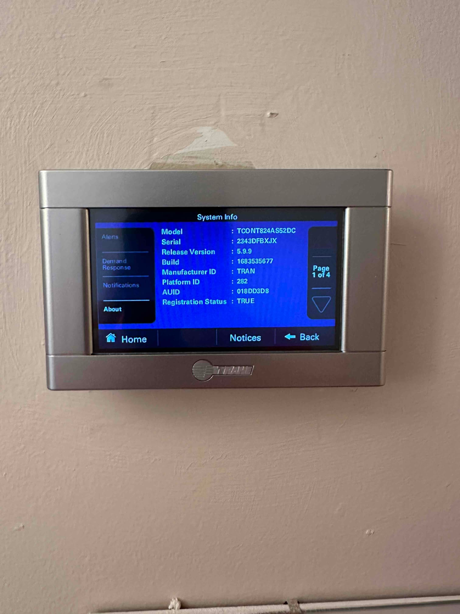 Wall-mounted touchscreen thermostat displays system information menu after installation, confirming device setup and interface operation.